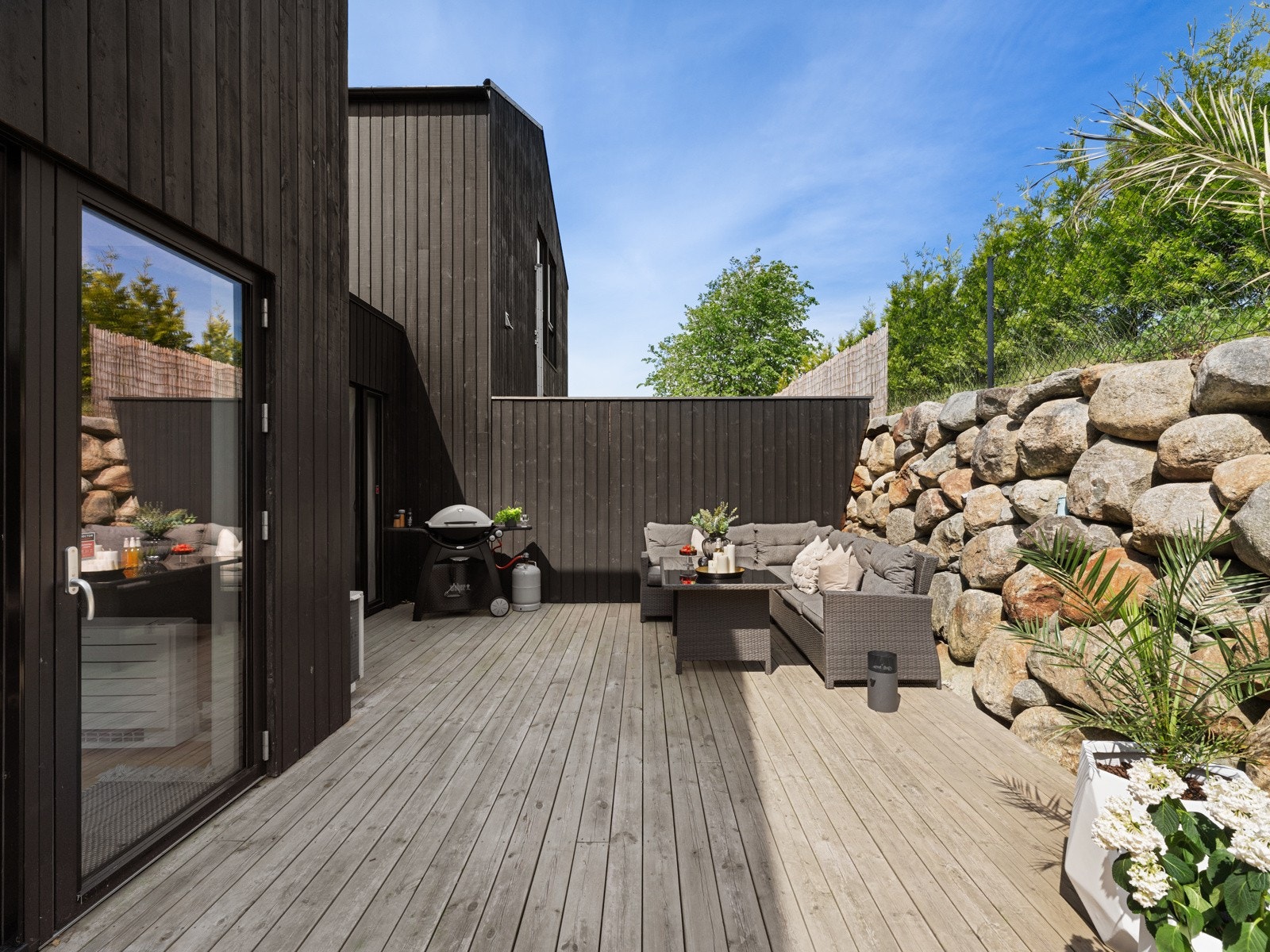 Skjermet terrasse med god plass til sittegrupper, spisebord og grill Galleribilde