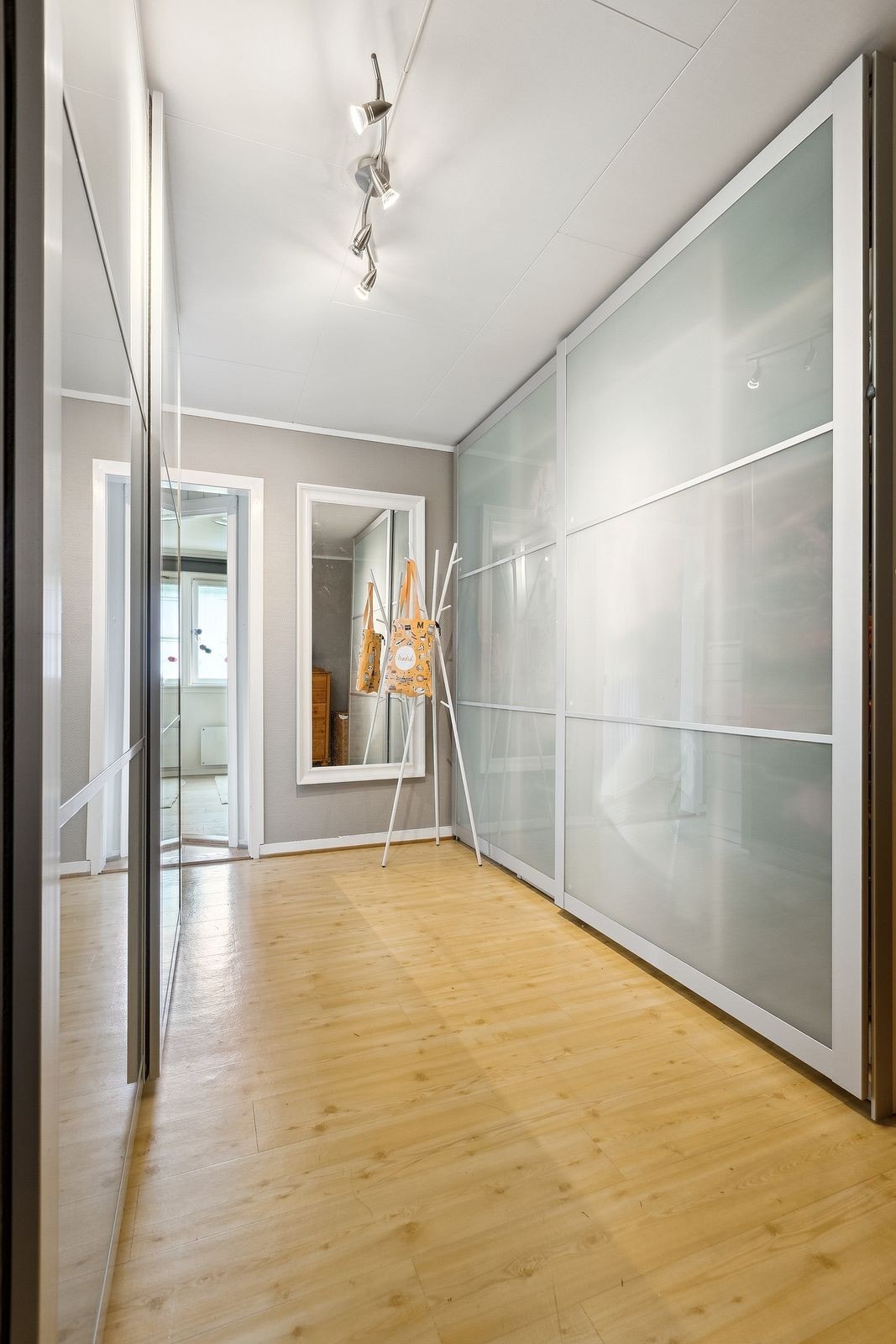 Fra boligens entrè kommer man inn i dette oppbevaringsrommet med skyvedørsgarderobe på begge sider Galleribilde