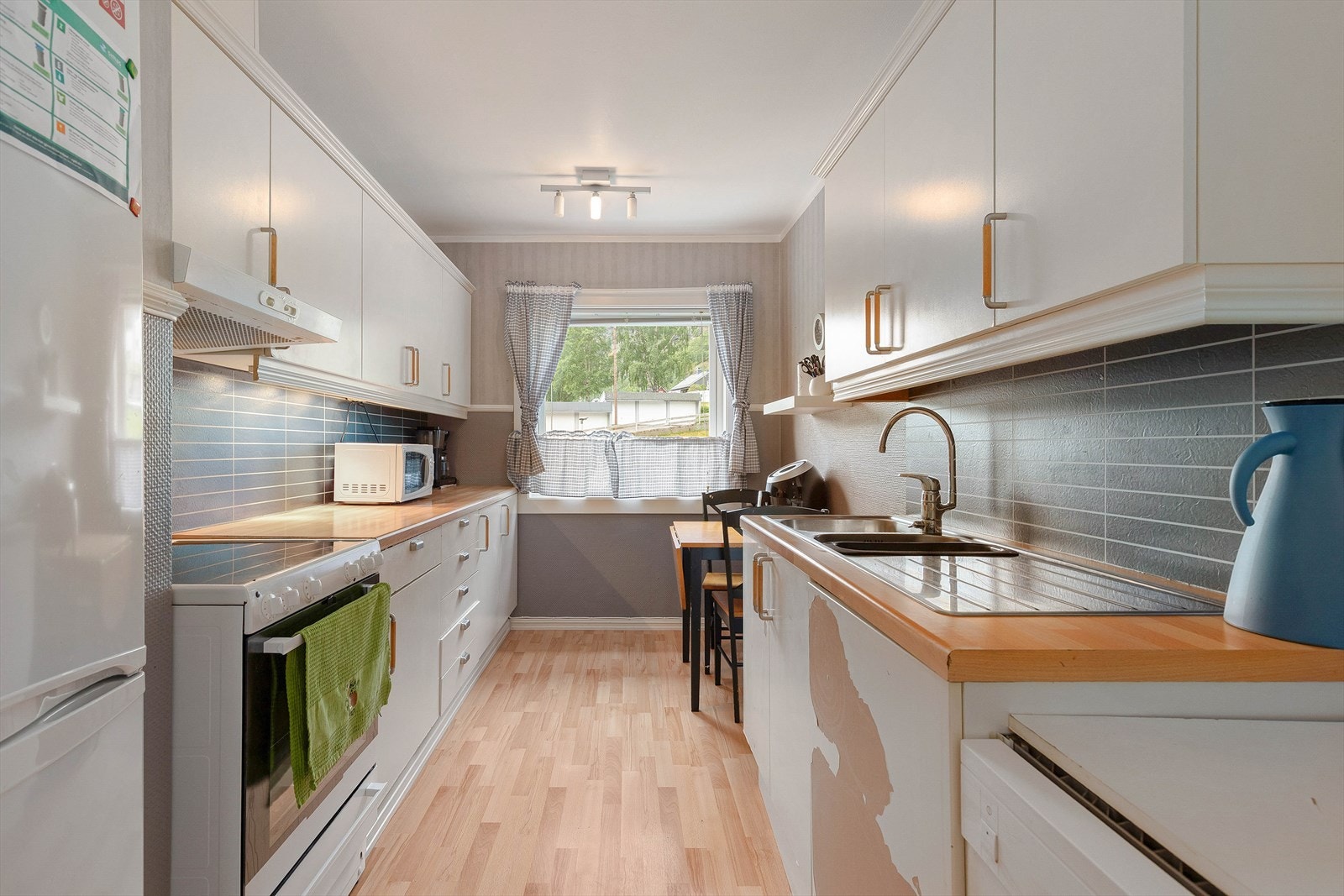 Kjøkkenet har innreiing med kvite glatte frontar, samt benkeplate av laminat. Det er skade på den eine kjøkkenfronten. Galleribilde