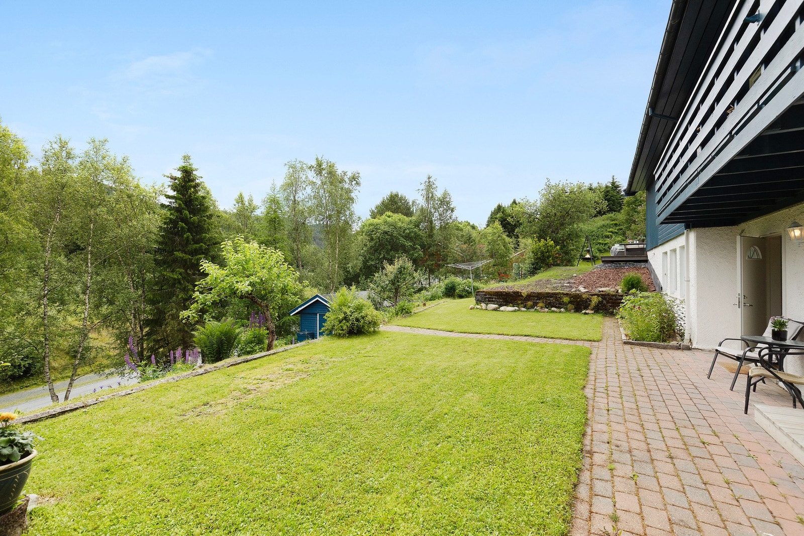 Den store, eide tomten byr på flere solrike uteplasser, en frodig hage over flere nivåer med frukttrær, bærbusker, grønnsaker og god boltreplass. Galleribilde