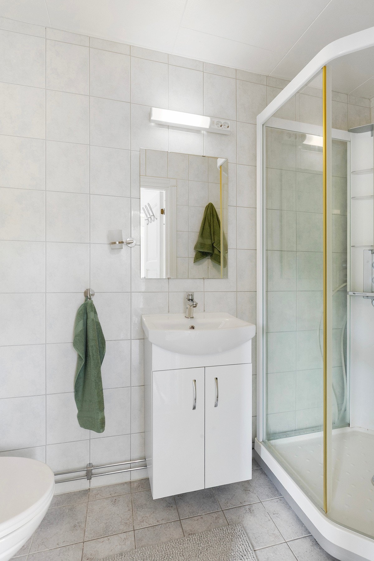 Praktisk flislagt baderom med dusjkabinett, wc og enkel innredning. Galleribilde