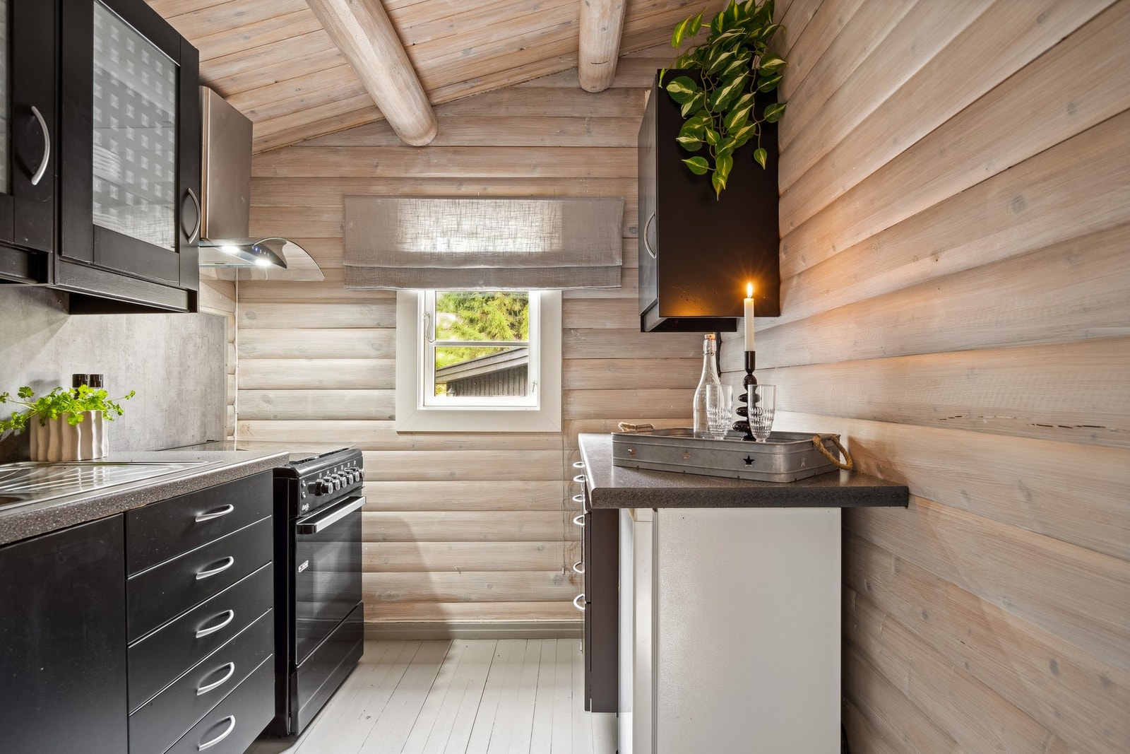 Kjøkkeninnredning fra 2023 med profilerte, sorte fronter, overskap med glass, benkeplater i laminat, dobbel oppvaskkum med ett-greps blandebatteri. Galleribilde