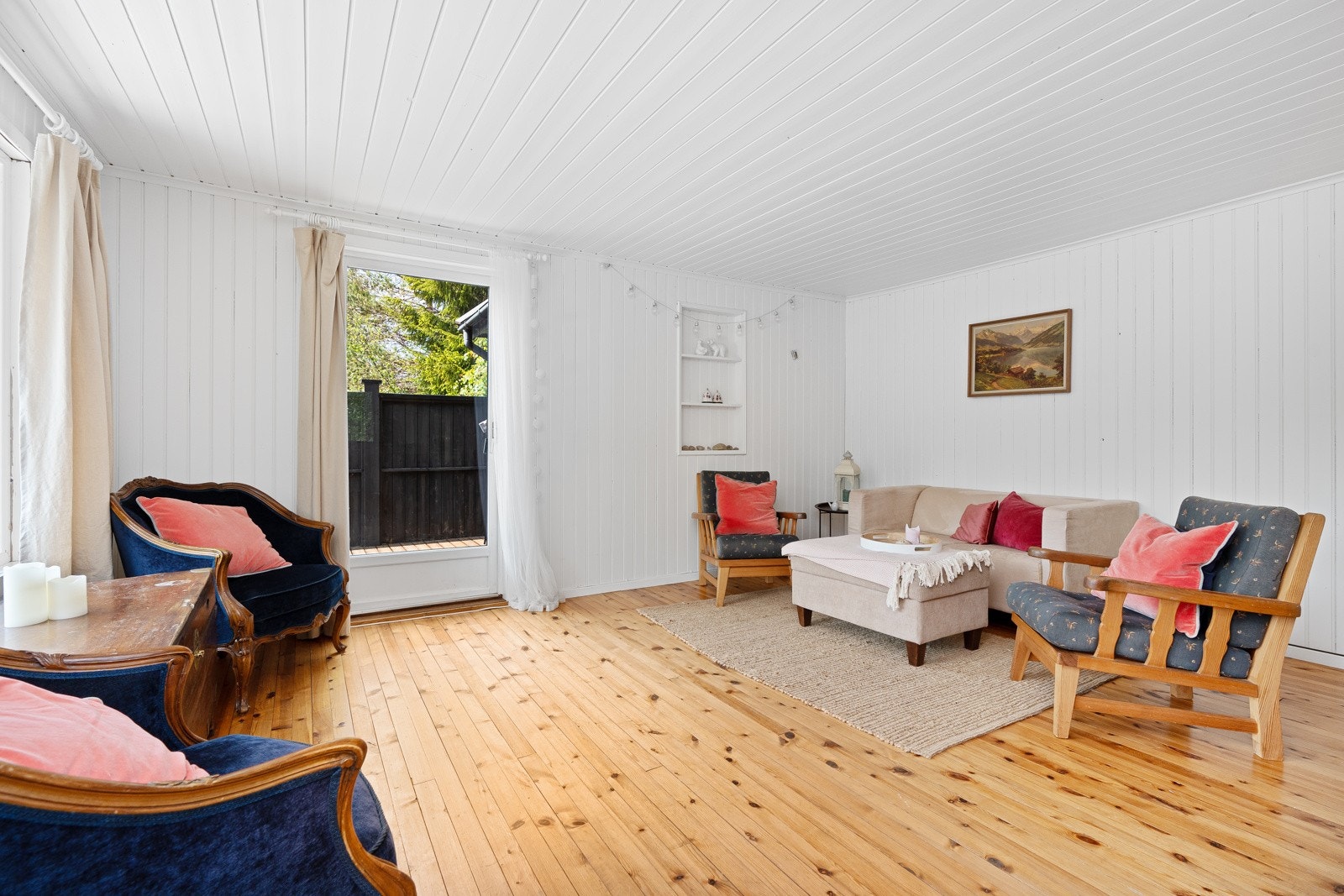 Hytta har en trivelig stue med tregulv, malt veggpanel, trapp til loftsetasjen og godt med naturlig lys fra vinduer på to sider. Galleribilde