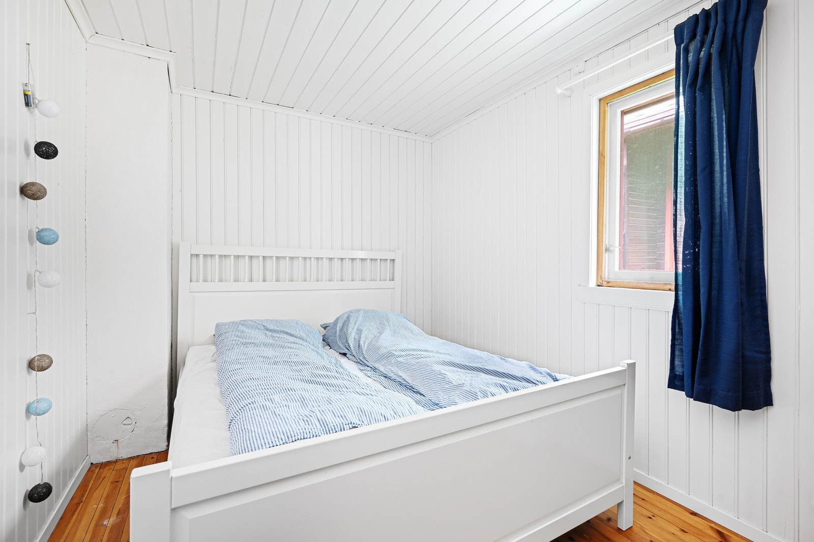 Hytta har et romslig soverom i første etasje som er lyst og trivelig med hvitmalt veggpanel og plass til dobbeltseng. Galleribilde