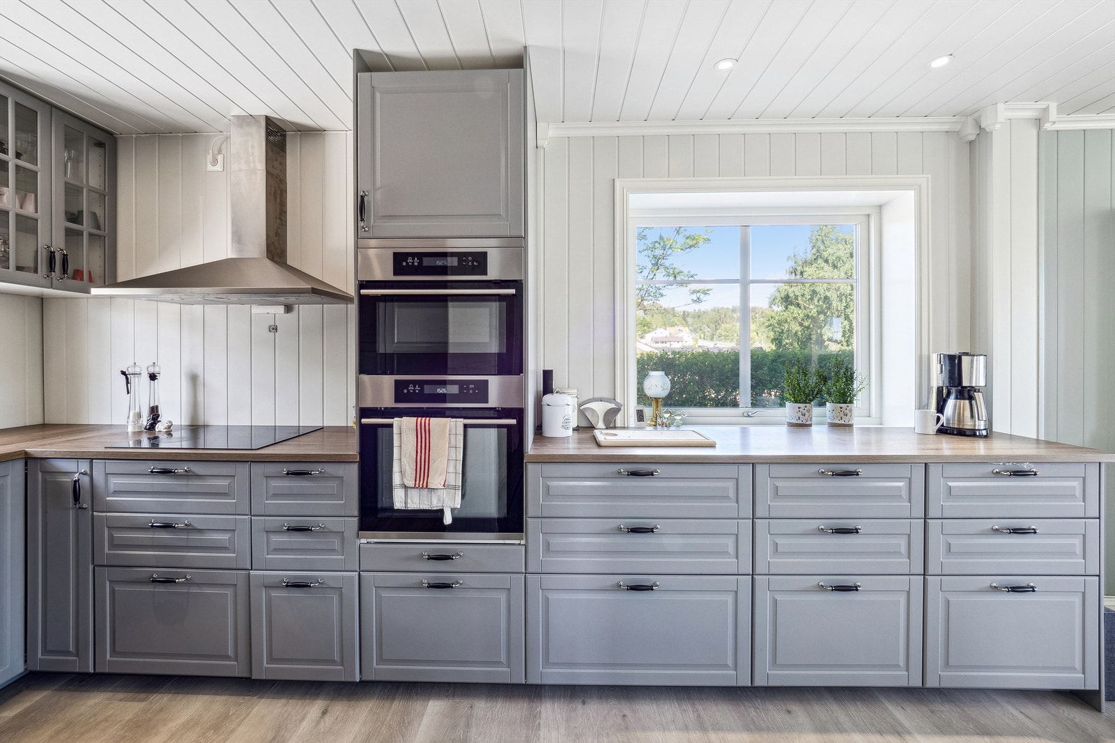 Kjøkken i grå profilert stil med integrerte hvitevarer på hovedplan. Galleribilde