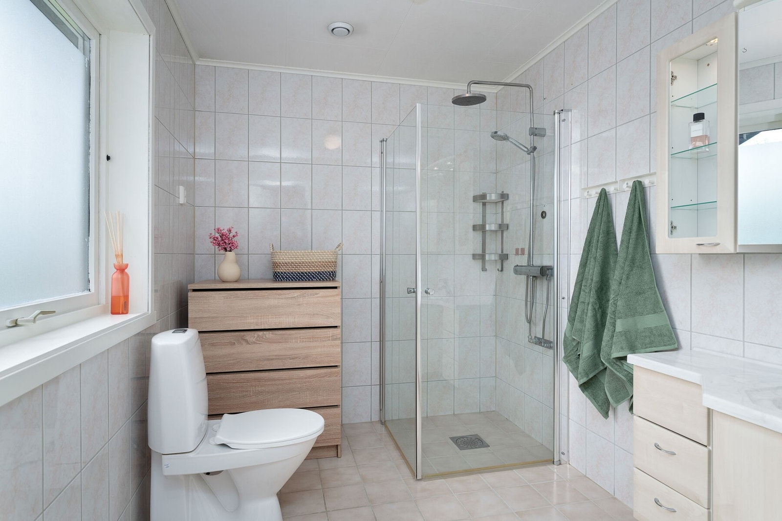 Badet er utstyrt med servant på innredning, toalett og dusjhjørne. Galleribilde