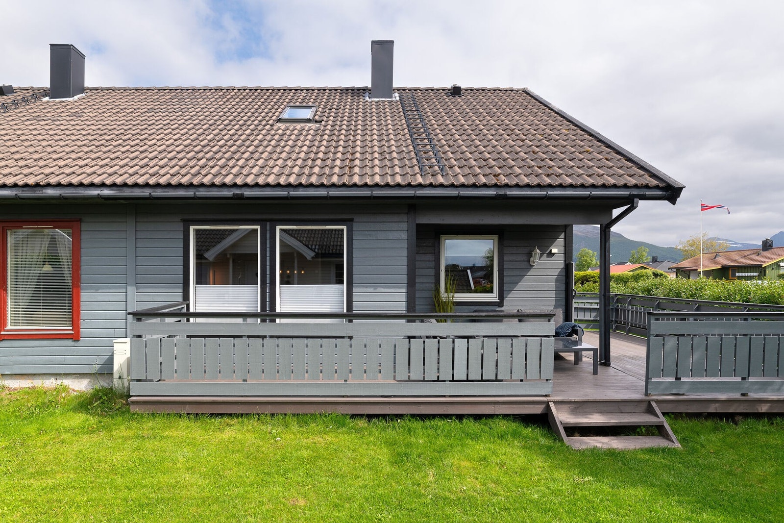 Fasade og uteområde. Utendørs er det opparbeidet hage med plen og beplantning. Galleribilde