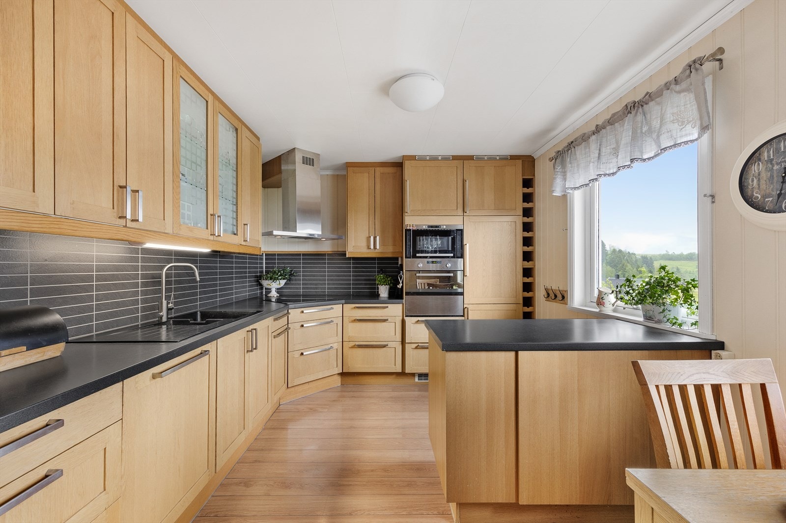 Kjøkkeninnredning med profilerte fronter, laminert benkeplate, nedfelt oppvaskkum med 1-greps blandebatteri og skylleplate mellom over og underskap Galleribilde