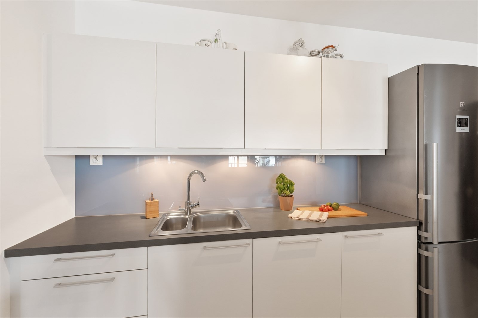 Kjøkkenet har lyse fronter, laminat benkeplate og integrert oppvaskmaskin. Galleribilde