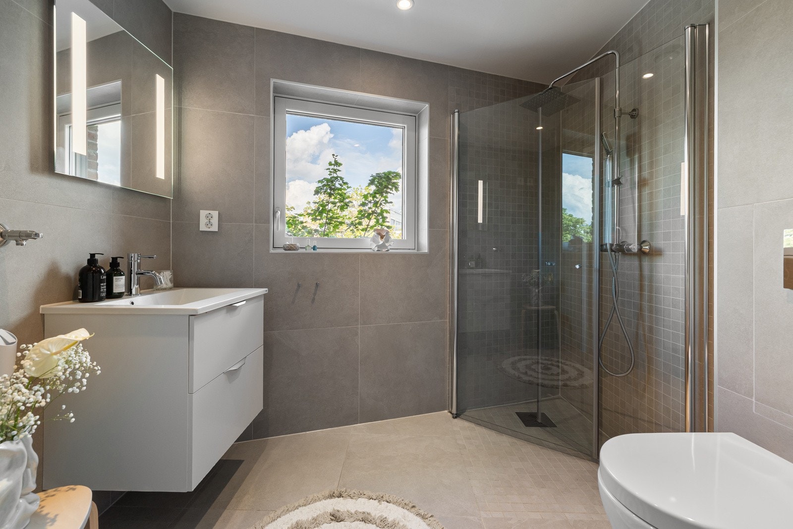 Praktisk servant med innredning, dusjhjørne med innfellbare glassdører og vegghengt toalett gir et stilrent og funksjonelt uttrykk. Galleribilde