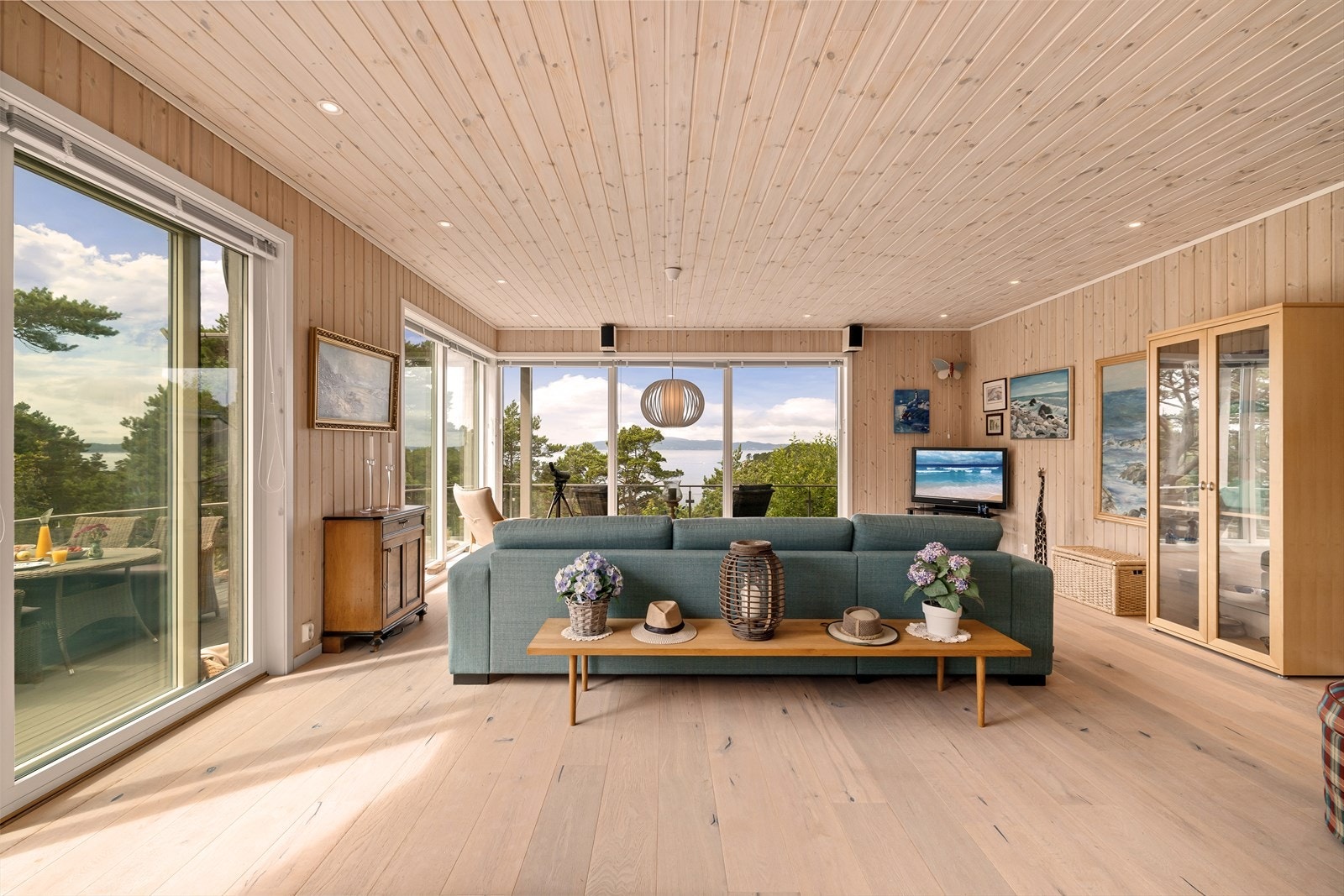 Lys og innbydende stue med store vinduer som rammer inn en vakker utsikt mot natur og sjø. Galleribilde
