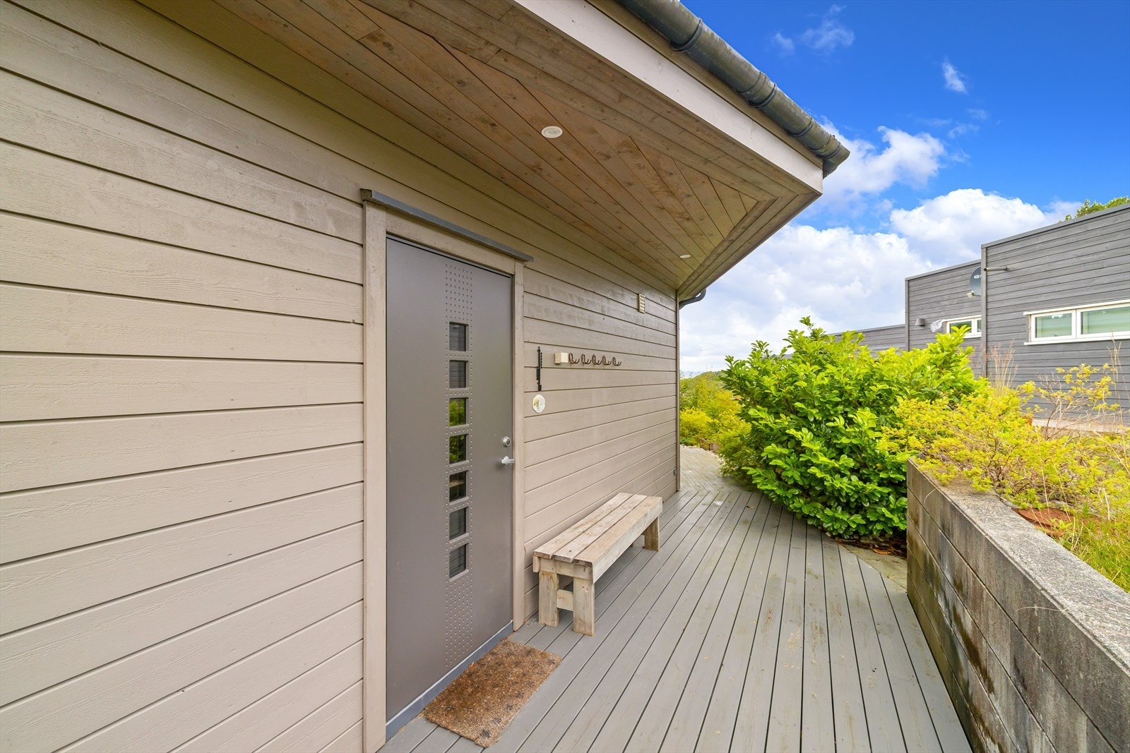 Moderne inngangsparti med stilrent design, omkranset av frodig vegetasjon. Galleribilde