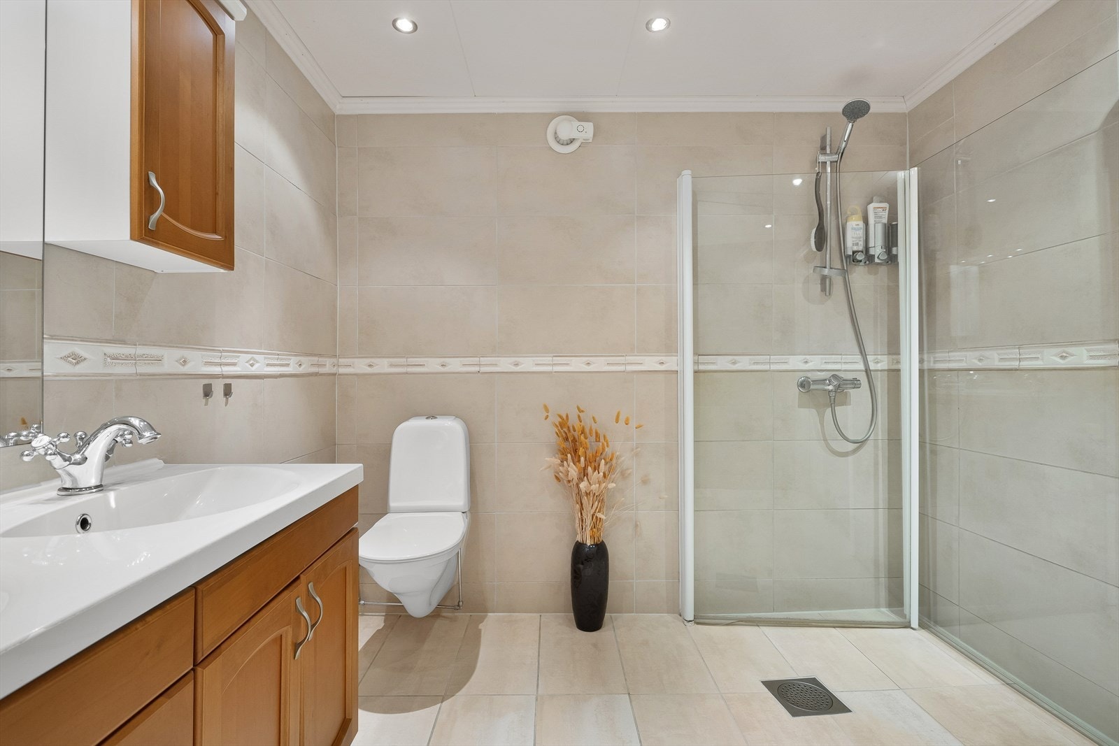 Badet inneholder dobbel servant med over- og underskap, vegghengt toalett og dusj med innfellbare dører. Galleribilde