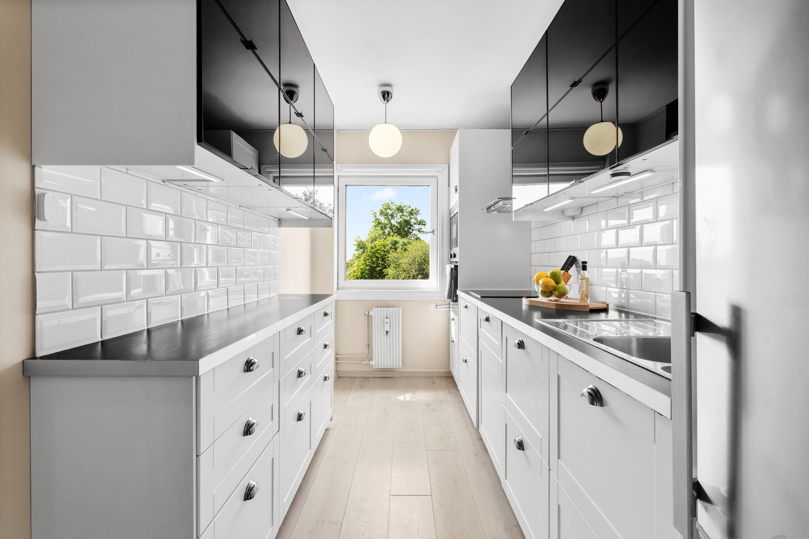 Kjøkkenet byr på god benkeplass og rikelig med oppbevaring. Her er det innredning med hvite speilfronter og bistrofliser over benk gir et stilrent uttrykk. Galleribilde