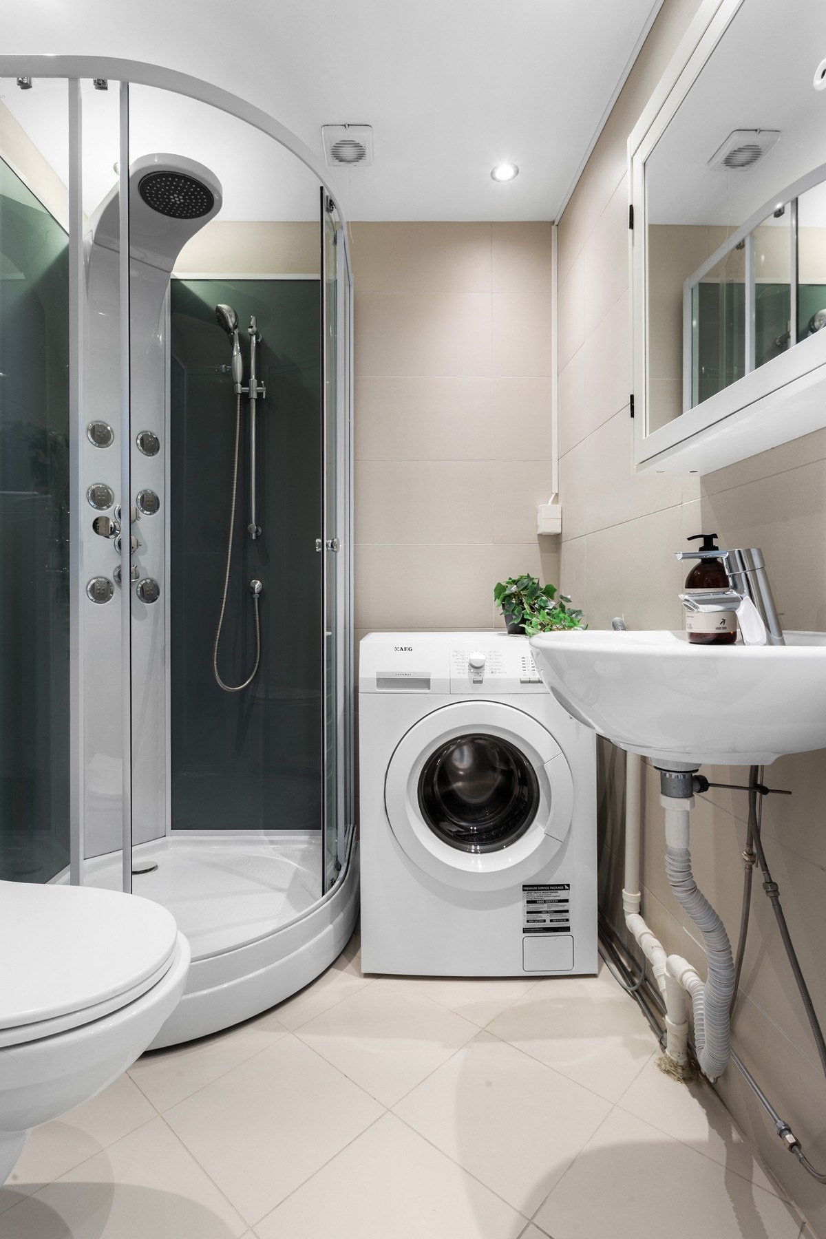 Pent helflislagt bad fra ca. 2015 med tidløs utforming. Badet inneholder dusjkabinett, vegghengt toalett, servant med speil og lys, samt opplegg for vaskemaskin. Galleribilde