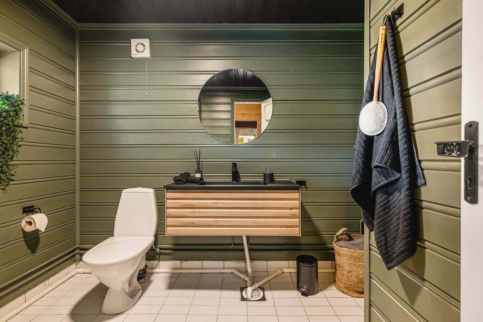 Badet er utstyrt med gulvmontert toalett, benkeskap med servant, dusjkabinett, opplegg for vaskemaskin og varmtvannsbereder. Galleribilde