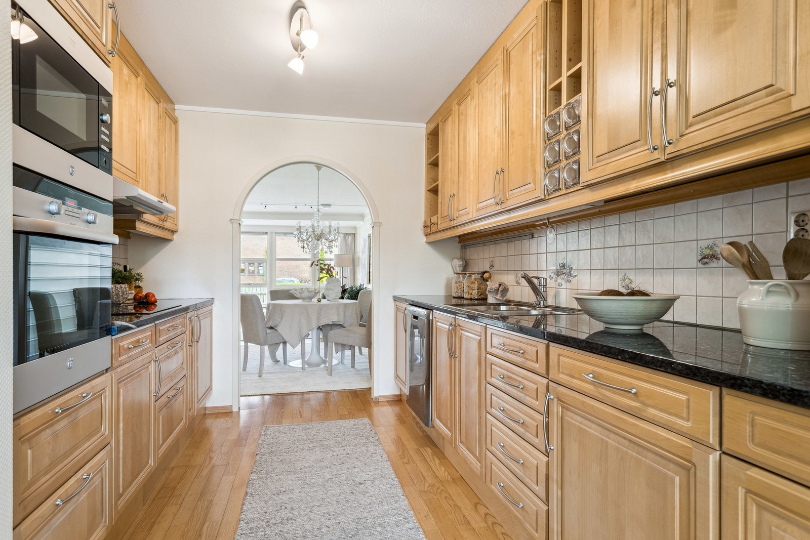 Kjøkkenet har en delvis åpen løsning og er innredet med Sigdal kjøkkeninnredning med klassiske, profilerte fronter i tre. Benkeplaten i stein gir et solid og tidløst uttrykk. Galleribilde