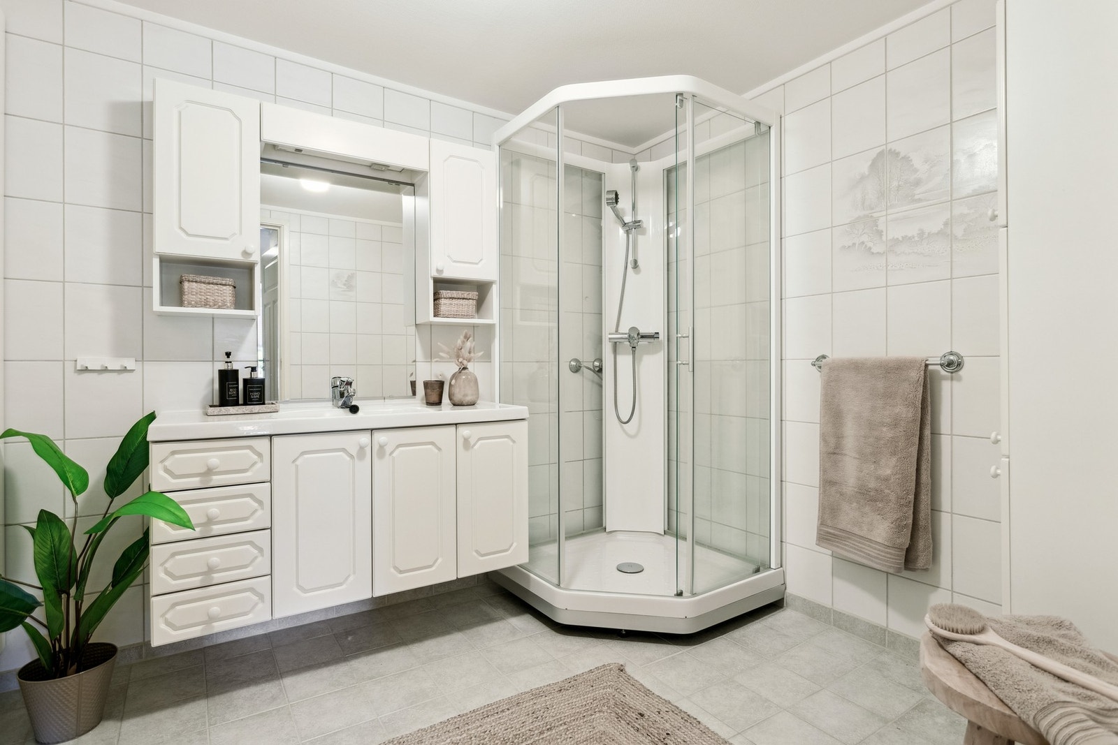 Badet er lyst og funksjonelt, med flislagte overflater som gir en solid og tidløs kvalitet, i tillegg til praktisk oppbevaringsplass. Galleribilde