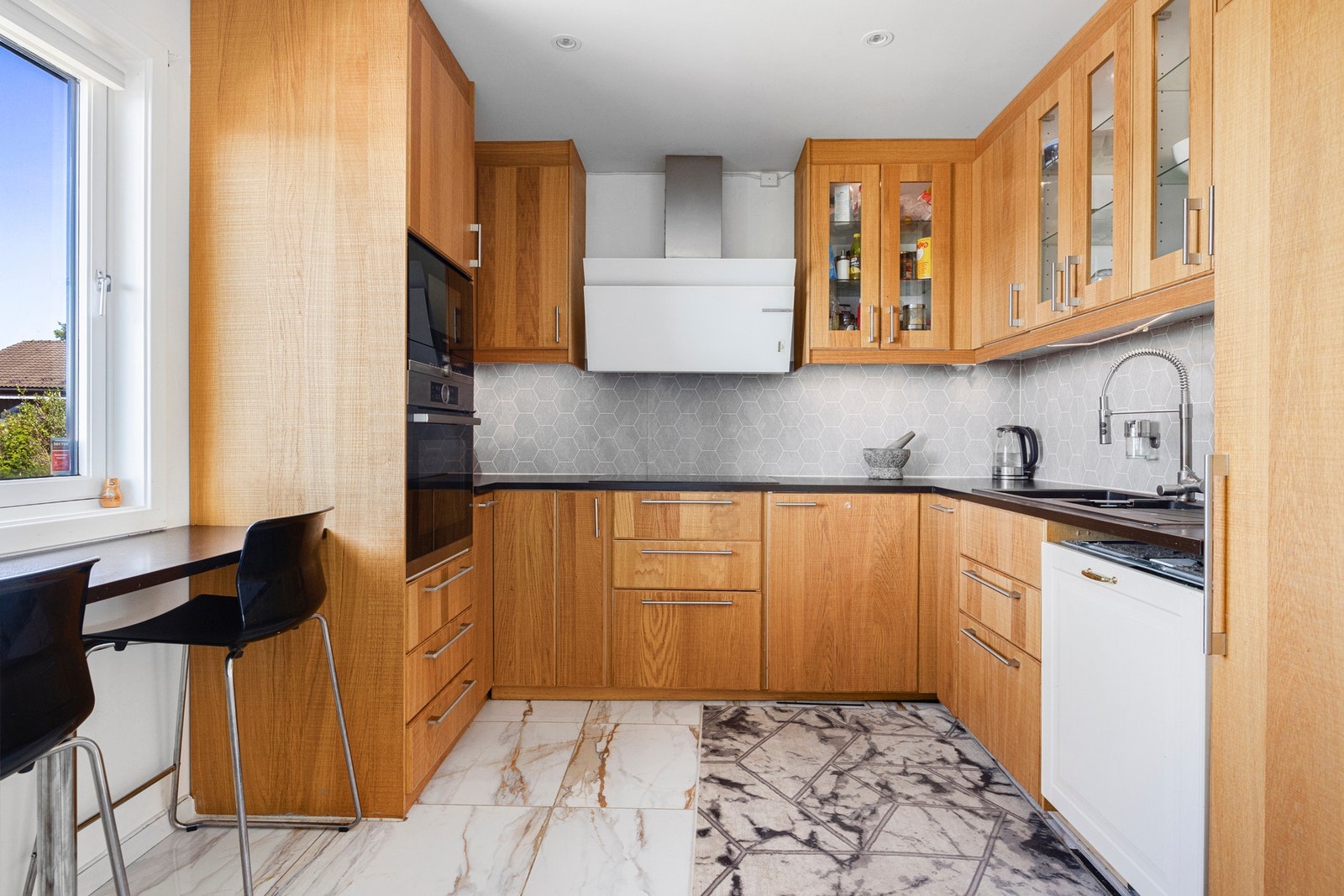 Kjøkkenet er innredet med integrerte hvitevarer som platetopp, stekeovn, oppvaskmaskin, kjøleskap samt ventilator over kokesone. Galleribilde