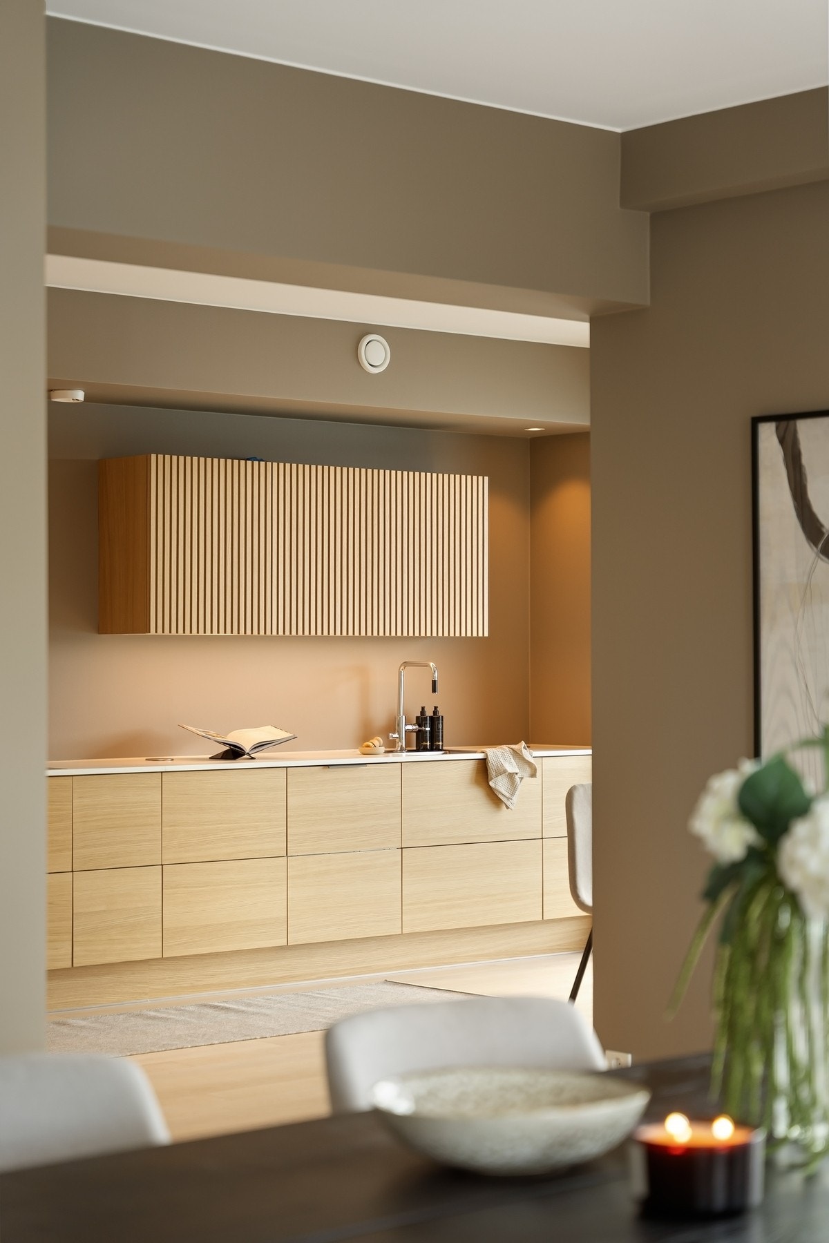 Kjøkkenet har både glatte og profilerte fronter og en hvit laminert benkeplate Galleribilde