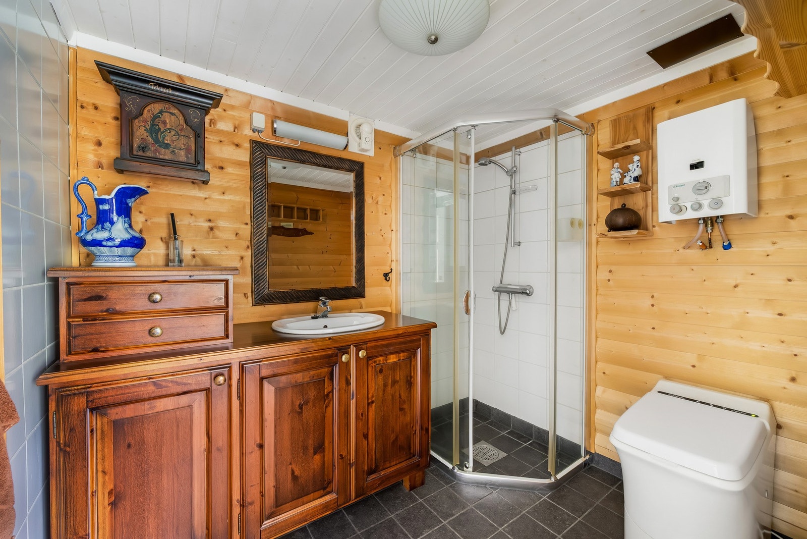 Rett innenfor soverommet ligger badet. Gulv med fliser og gulvvarme. Dusjkabinett og forbrenningstoalett. Galleribilde