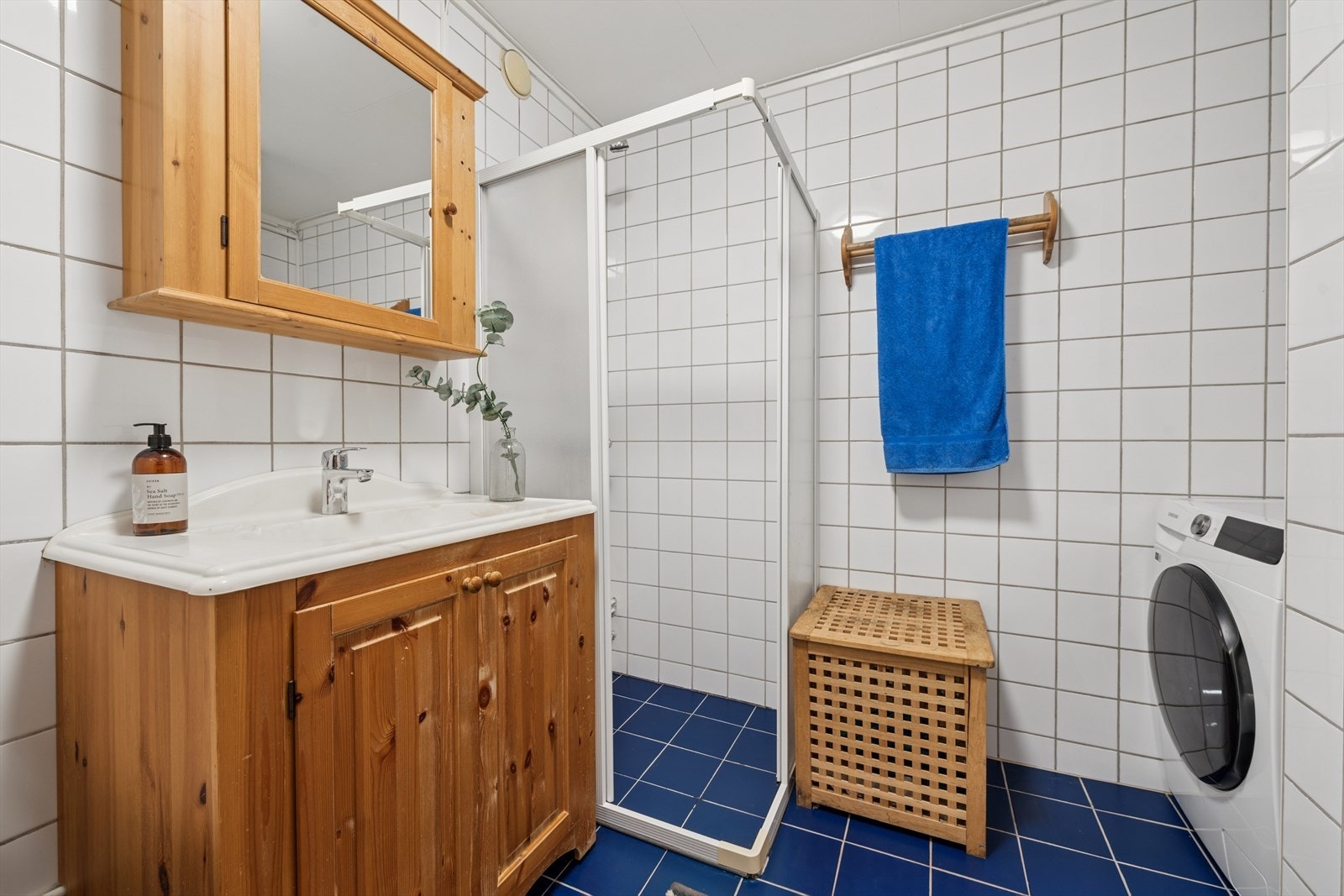 Badet er innredet med nedfelt servant, toalett, dusjhjørne med glassvegger og opplegg for vaskemaskin. Galleribilde