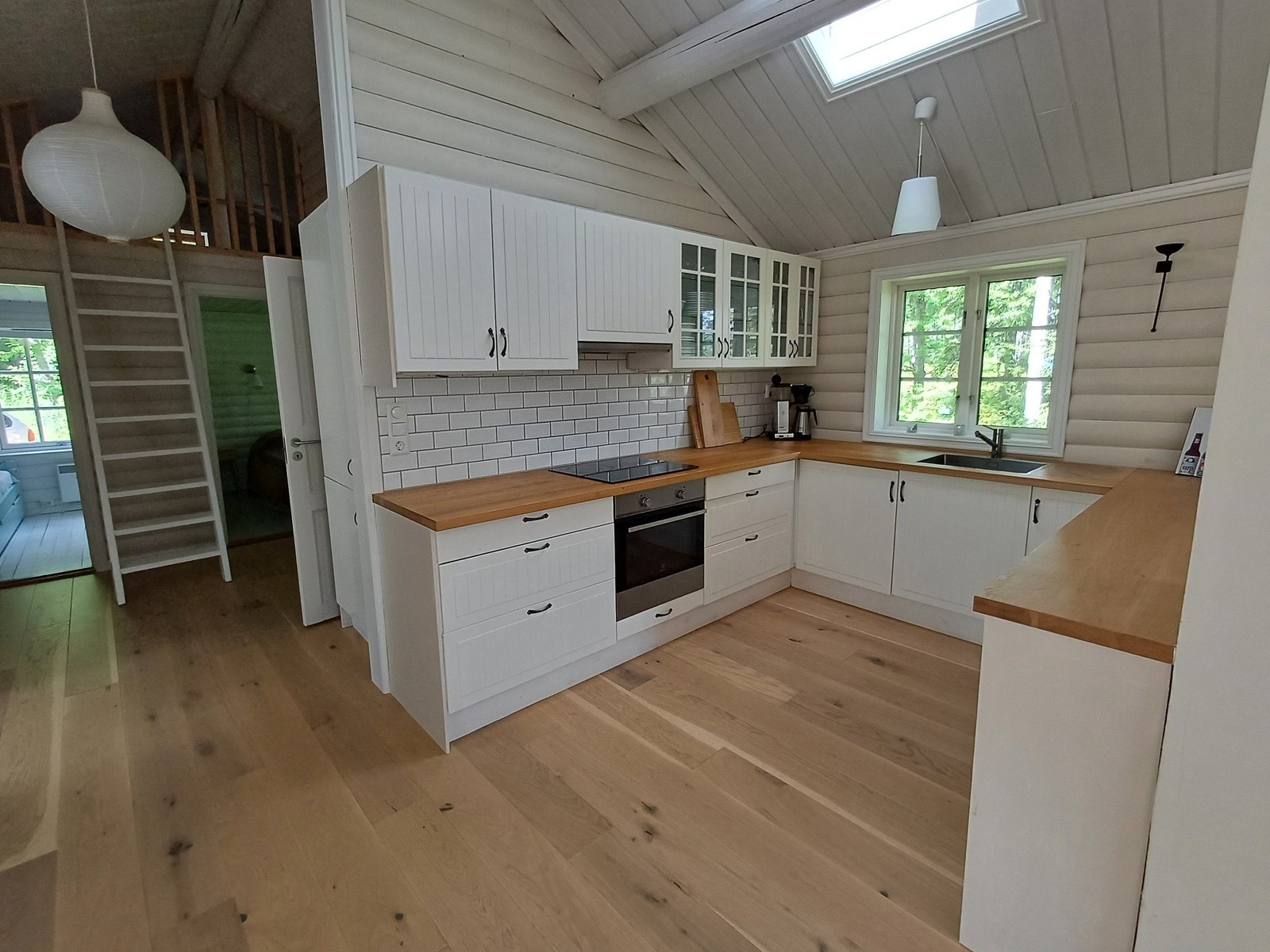 Kjøkkenet har åpen løsning med pen hvit innredning og god arbeidsflate i heltre. Integrert kjøleskap, koketopp, stekeovn og oppvaskmaskin Galleribilde