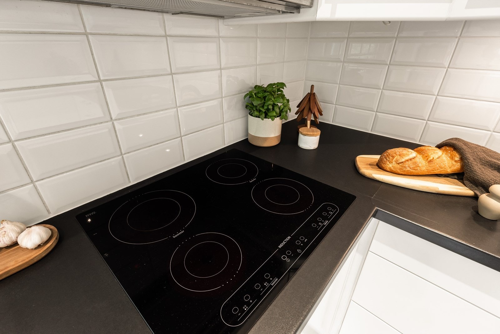 Induksjonsplatetopp og fliser mellom benkeplate og overskap. Galleribilde