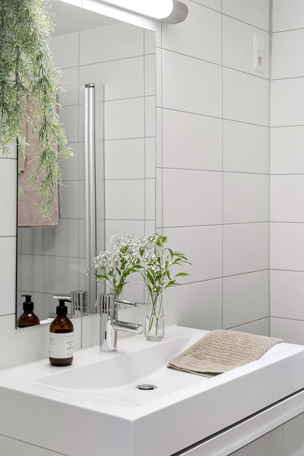 Badet inneholder dusjhjørne med innfellbare glassdører, gulvstående toalett og baderomsinnredning med skuffer, servant med blandebatteri fra Grohe og speil med belysning. Det er opplegg for vaskemaskin og mekanisk avtrekk. Galleribilde