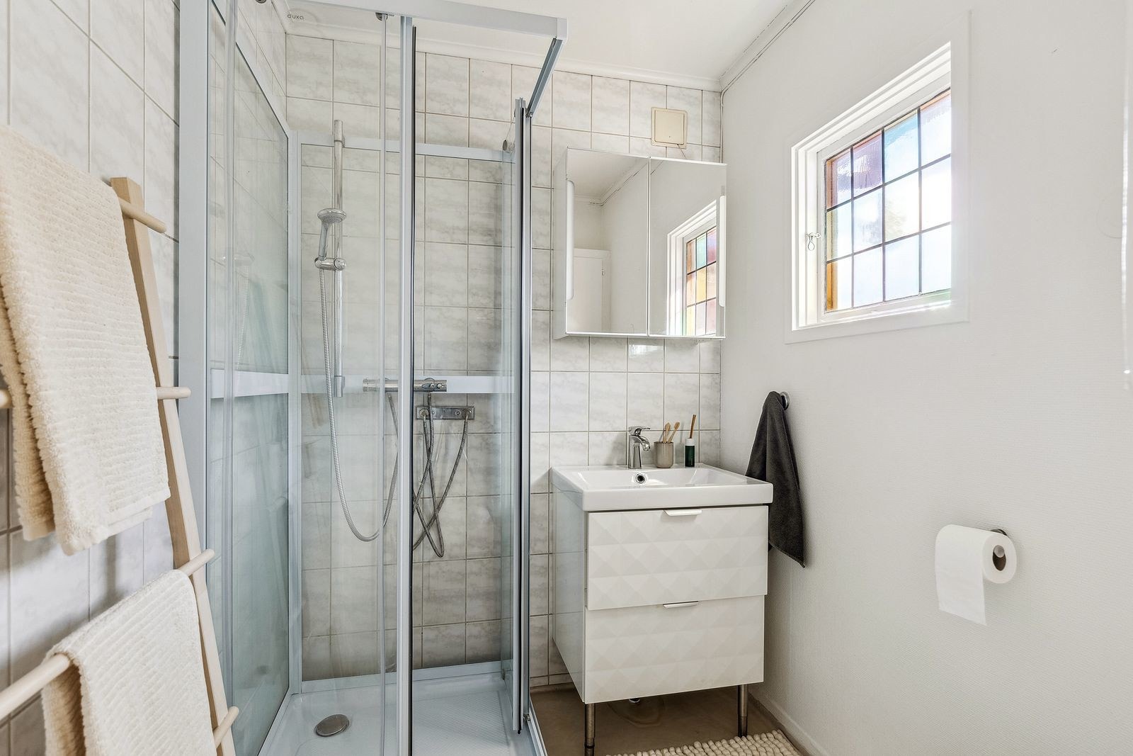 Badet i 1. etasje er utstyrt med dusjkabinett, håndvask med underskap, og gulvmontert klosett. Galleribilde