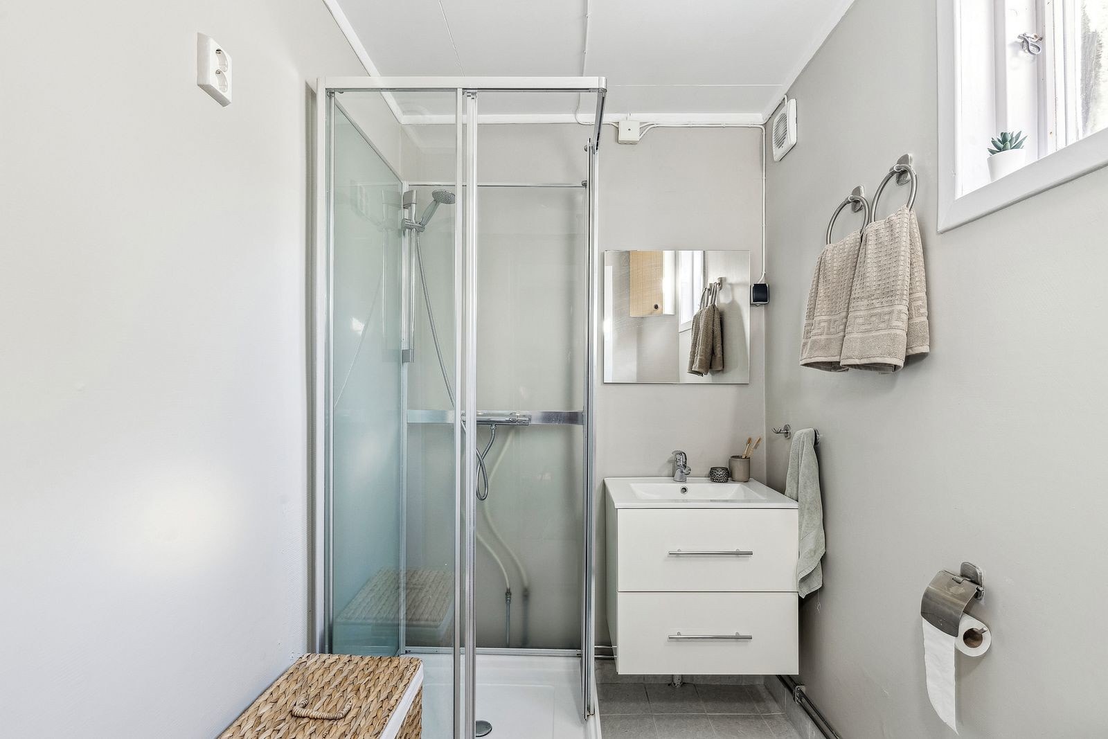 Bad med dusjkabinett, håndvask og toalett. Videre har rommet servant med underskap/speil, dusjkabinett og gulvmontert klosett. Galleribilde