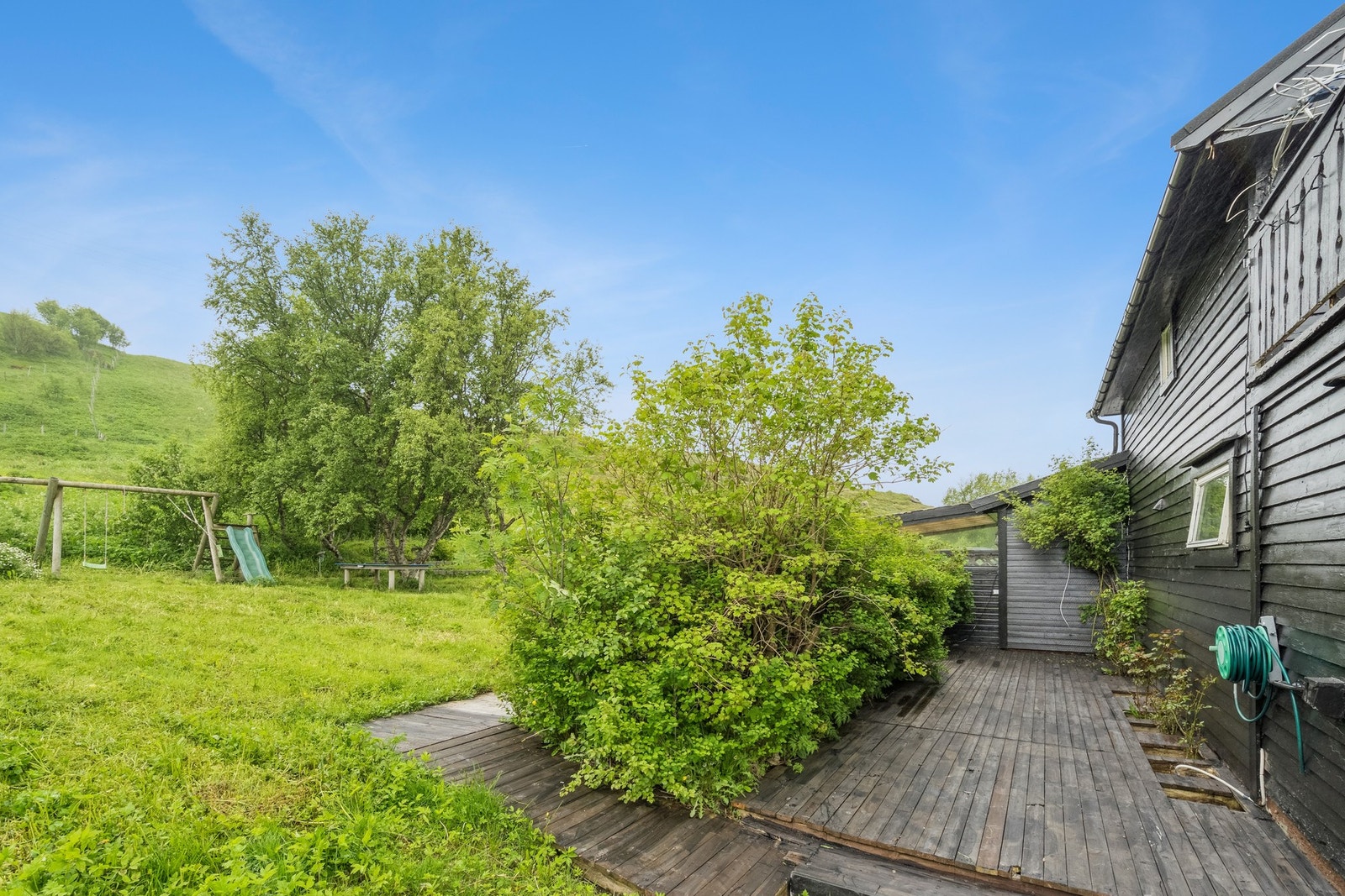 Terrasse som strekker seg rundt store deler av boligen. Galleribilde