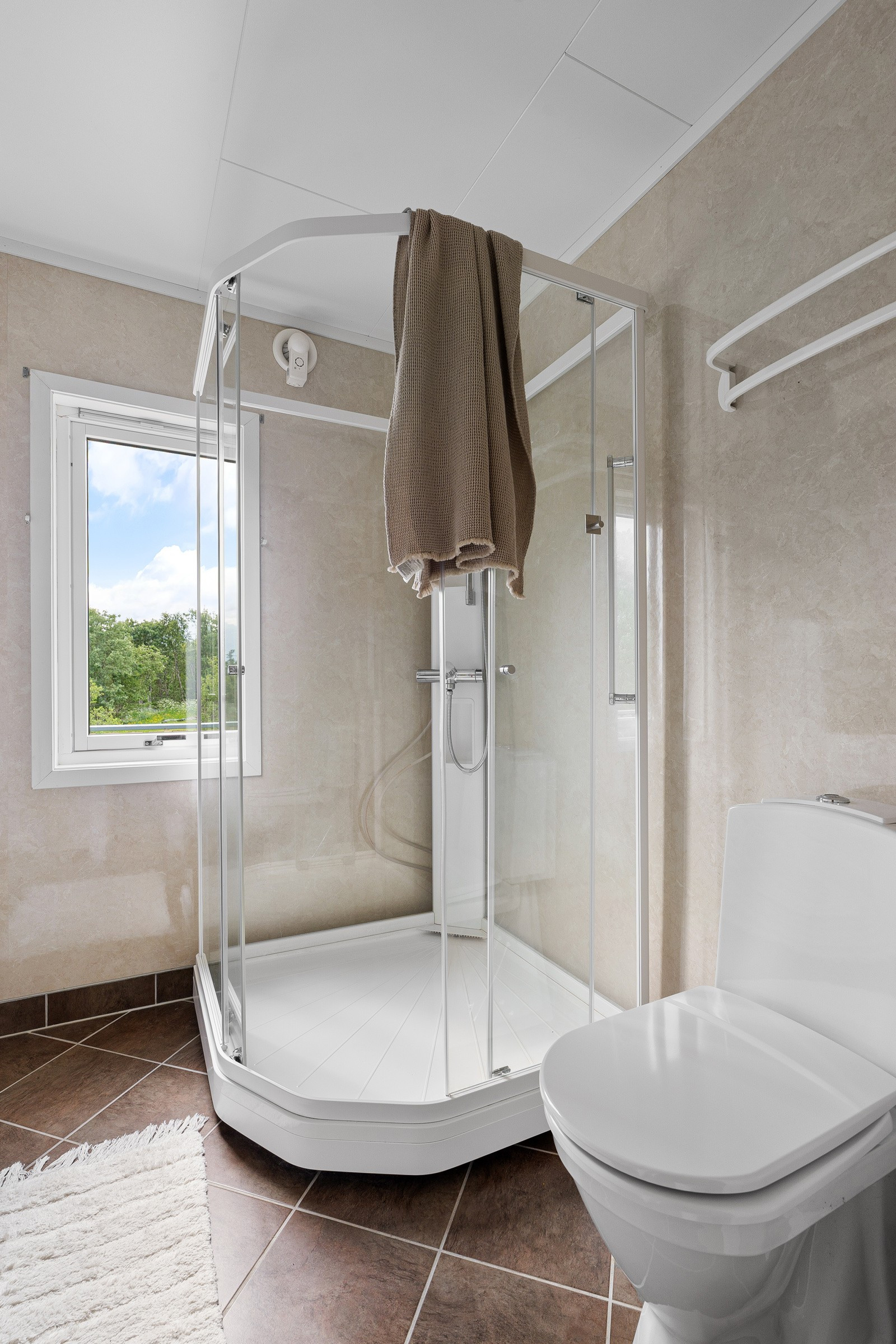 Bad/wc i hovedetasje med fliser på gulv, gulvvarme og dusjkabinett for minimal fuktbelastning.