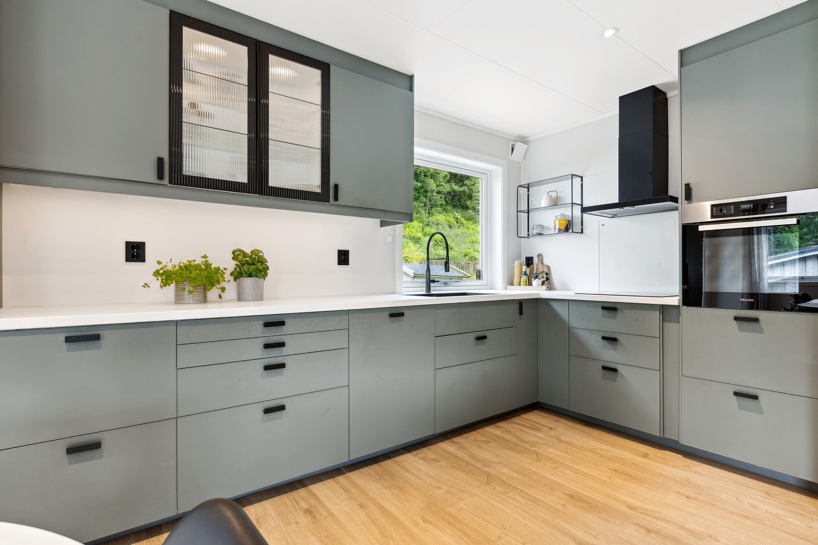 Moderne kjøkken fra 2023 med glatte fronter og lys benkeplate. Galleribilde