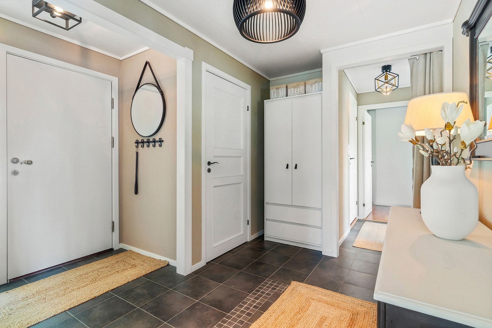 Romslig hall med flislagte gulv, dør midt på bildet er til WC rom. Galleribilde