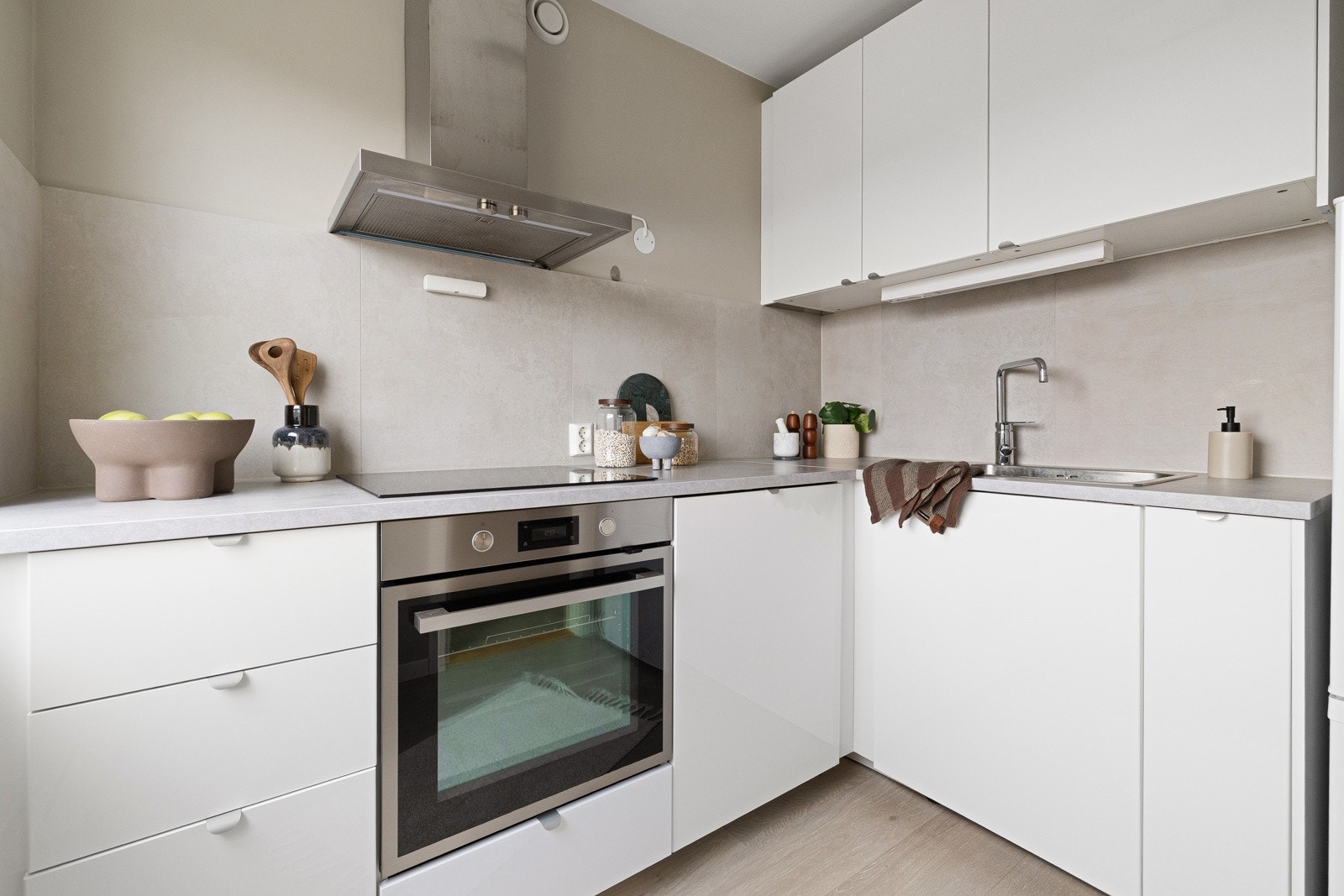Lys og moderne kjøkkeninnredning fra 2021 med god skap- og benkeplass. Innredningen har hvite glatte fronter og laminert benkeplate med nedfelt oppvaskkum. Både fint og praktisk med fliser i benkeryggen og belysning under overskapene. Galleribilde