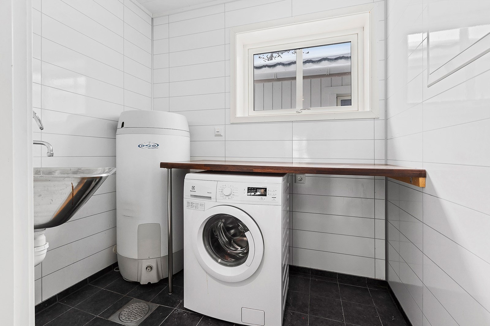 Vaskerommet er praktisk plassert rett ved utgangsdøra. Skyllekar, gulvvarme og en liten benk over vaskemaskin/ tørketrommel Galleribilde