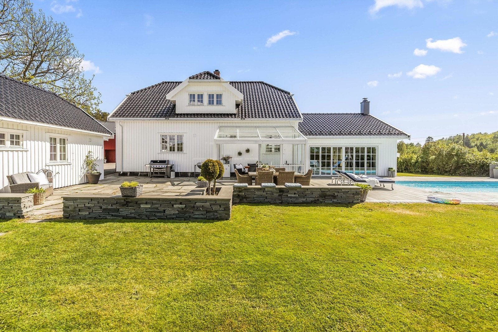 Uteområdet er pent inndelt i forskjellige soner som basseng, hagestue, spiseområde og grill-sone. Her kan barna fint sparke ball på den flate og store plenen. Galleribilde