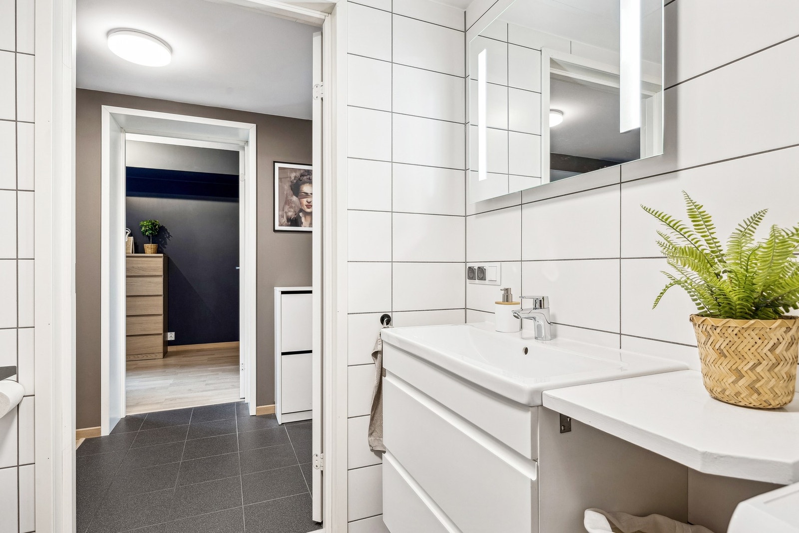 Badet er innredet med vegghengt servantinnredning med speil og belysning, dusjhjørne med glassdører, vegghengt toalett, samt opplegg for vaskemaskin. Galleribilde