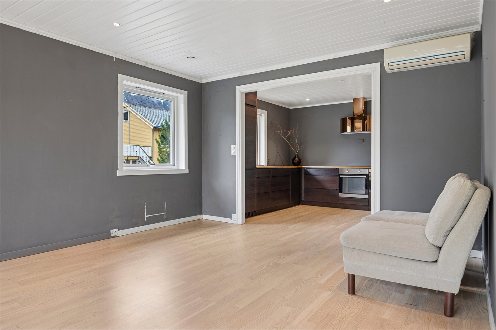 Den brede åpningen mellom stue og kjøkken gir en naturlig flyt mellom rommene, noe som både fremmer sosialt samvær og slipper inn rikelig med lys. Galleribilde