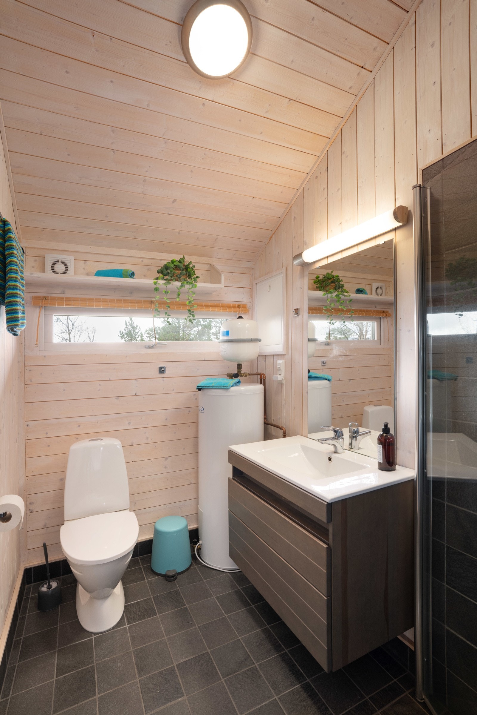 Baderomsinnredning med helstøpt servantplate, gulvmontert klosett og dusjhjørnet med innfellbare glassvegger. Galleribilde