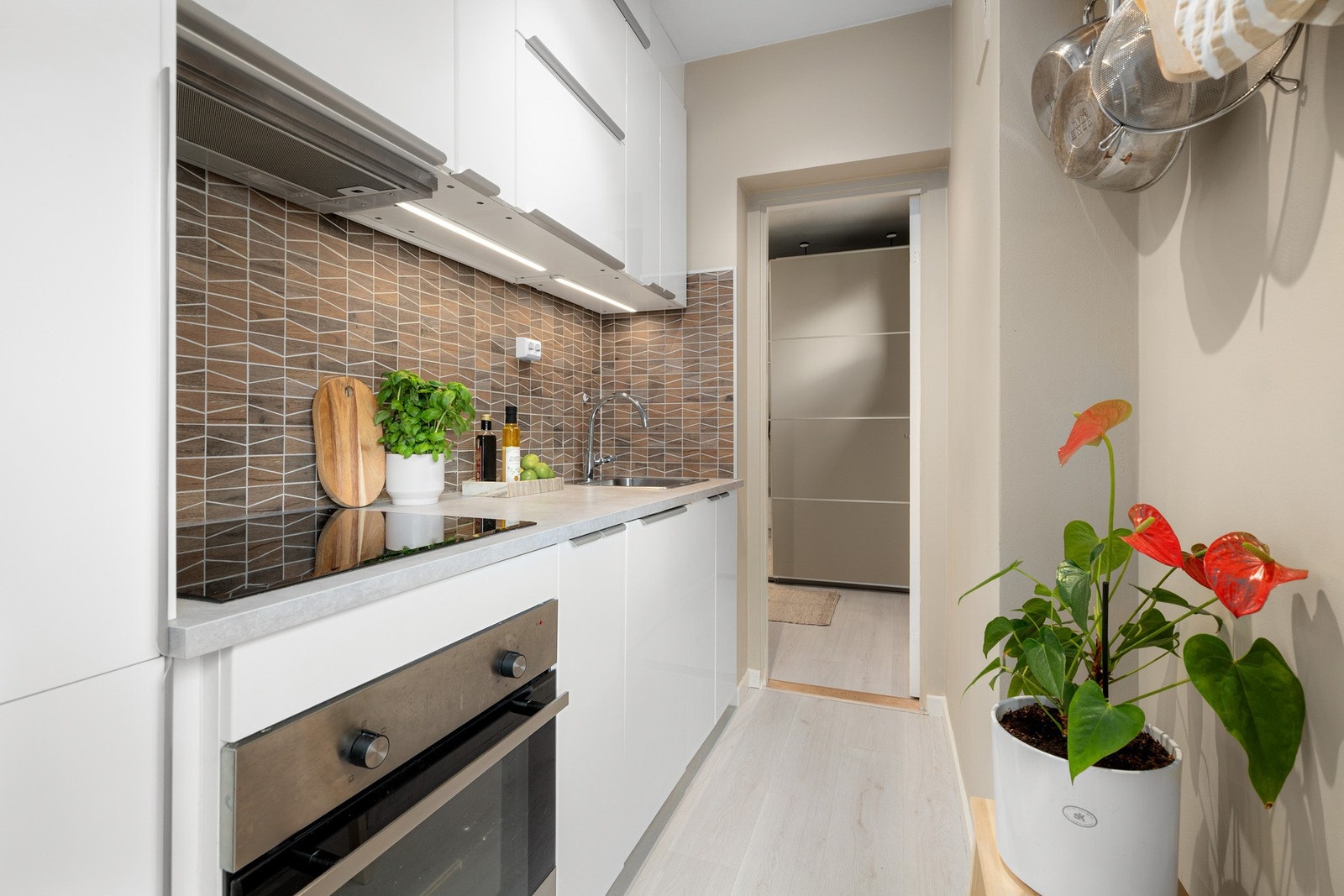 Kjøkkenet er åpent og effektivt innredet med lyse, glatte fronter i høyglans og en laminat benkeplate Galleribilde