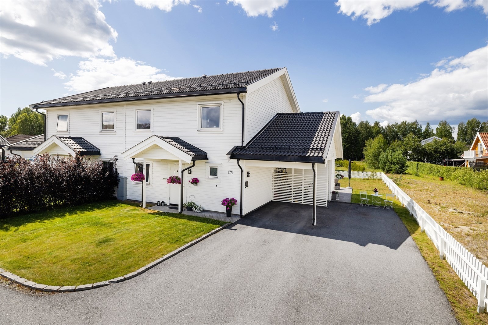 Tomten er videre opparbeidet med asfaltert gårdsplass med kantstein, hekk og gressplen på framsiden av boligen. Her får man også morgensolen. Carport med EL-bil lader. Galleribilde