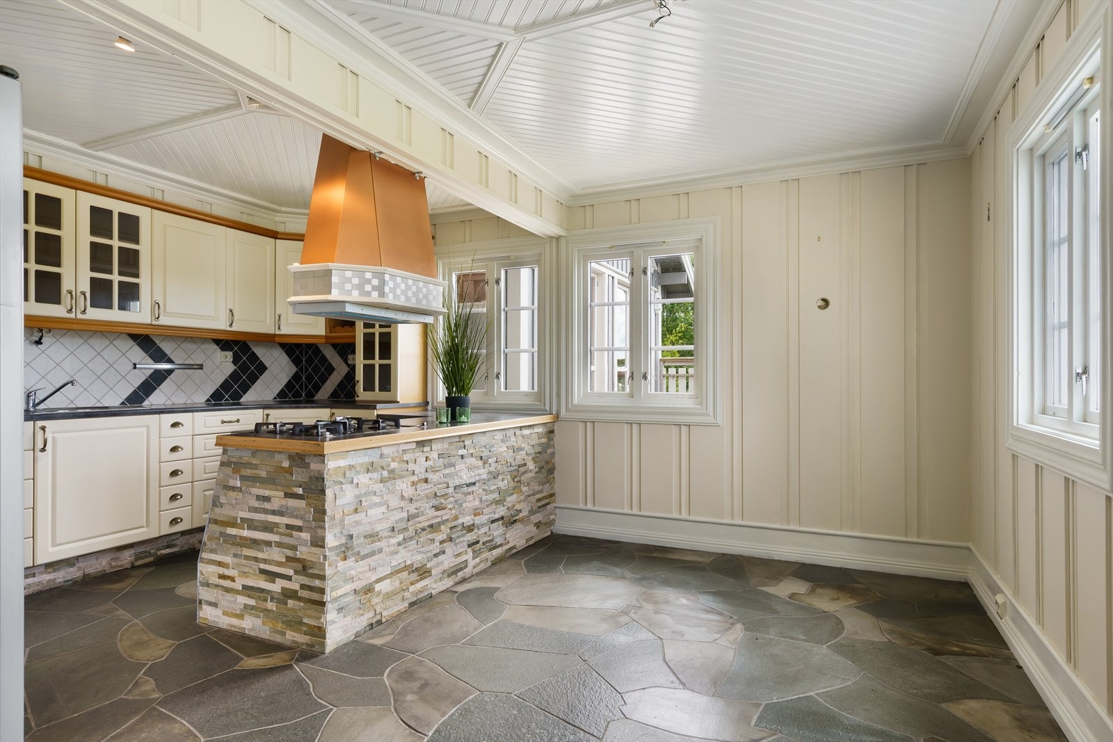 Kjøkkenet har innredning med hvite, profilerte fronter i over- og underskap, hvor noen overskap har glassfelt. Galleribilde