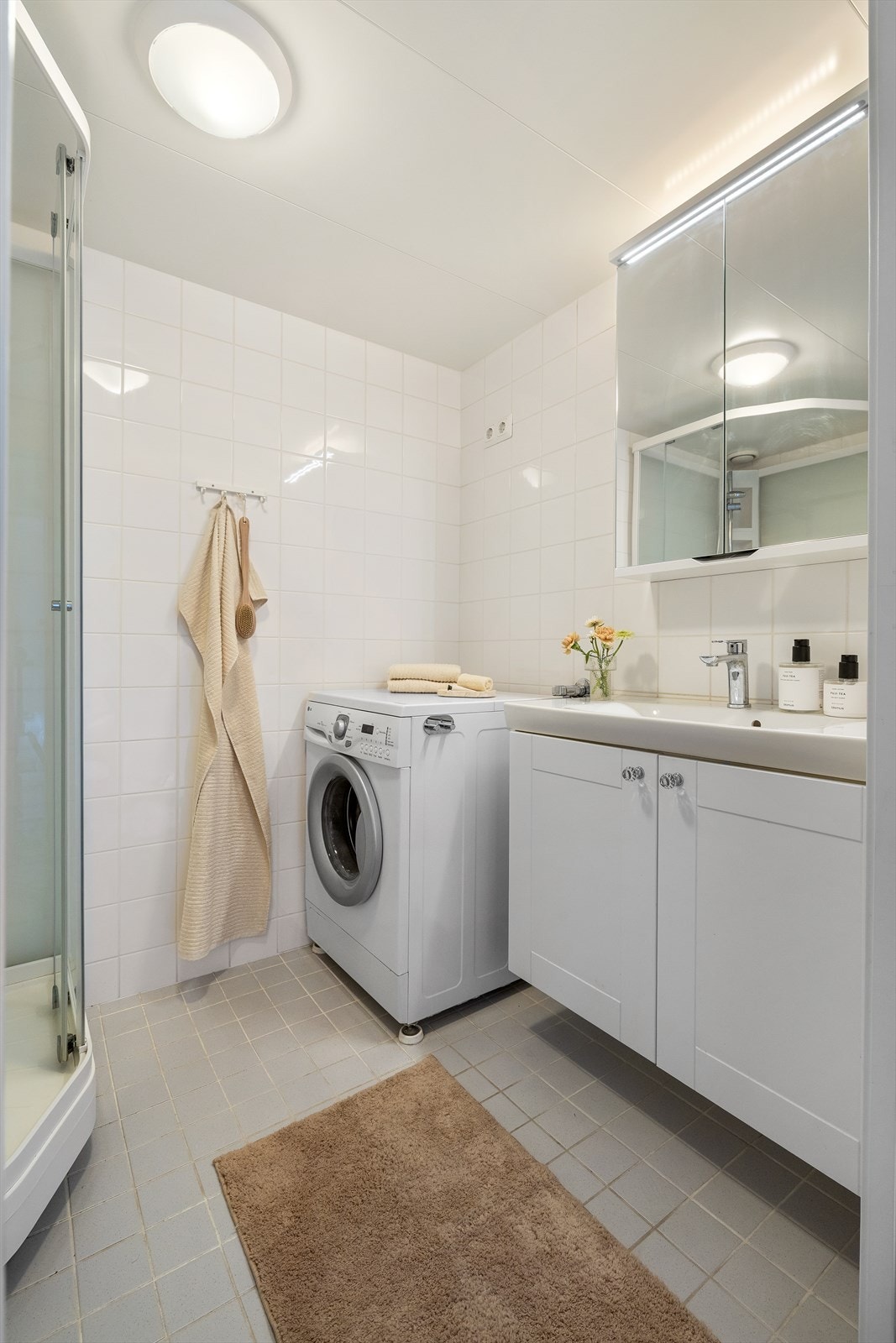 Badet har varmekabler i gulvet, opplegg til vaskemaskin, toalett, dusj, samt baderomsinnredning med servant med skap og skap med speildører. Galleribilde