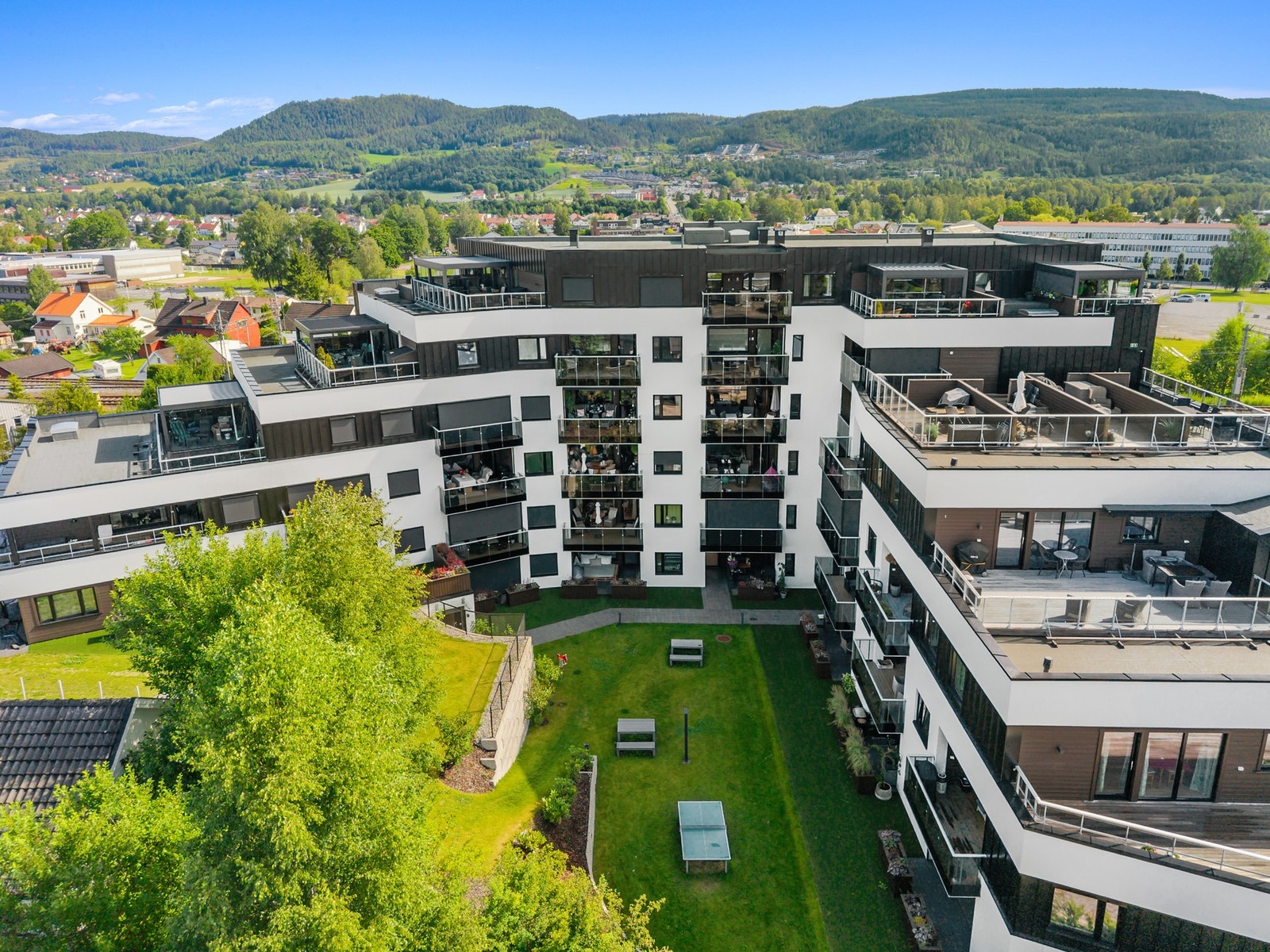 Tomten er pent opparbeidet med plenarealer, steinbelagte gangstier, sittebenker og diverse beplantning Galleribilde