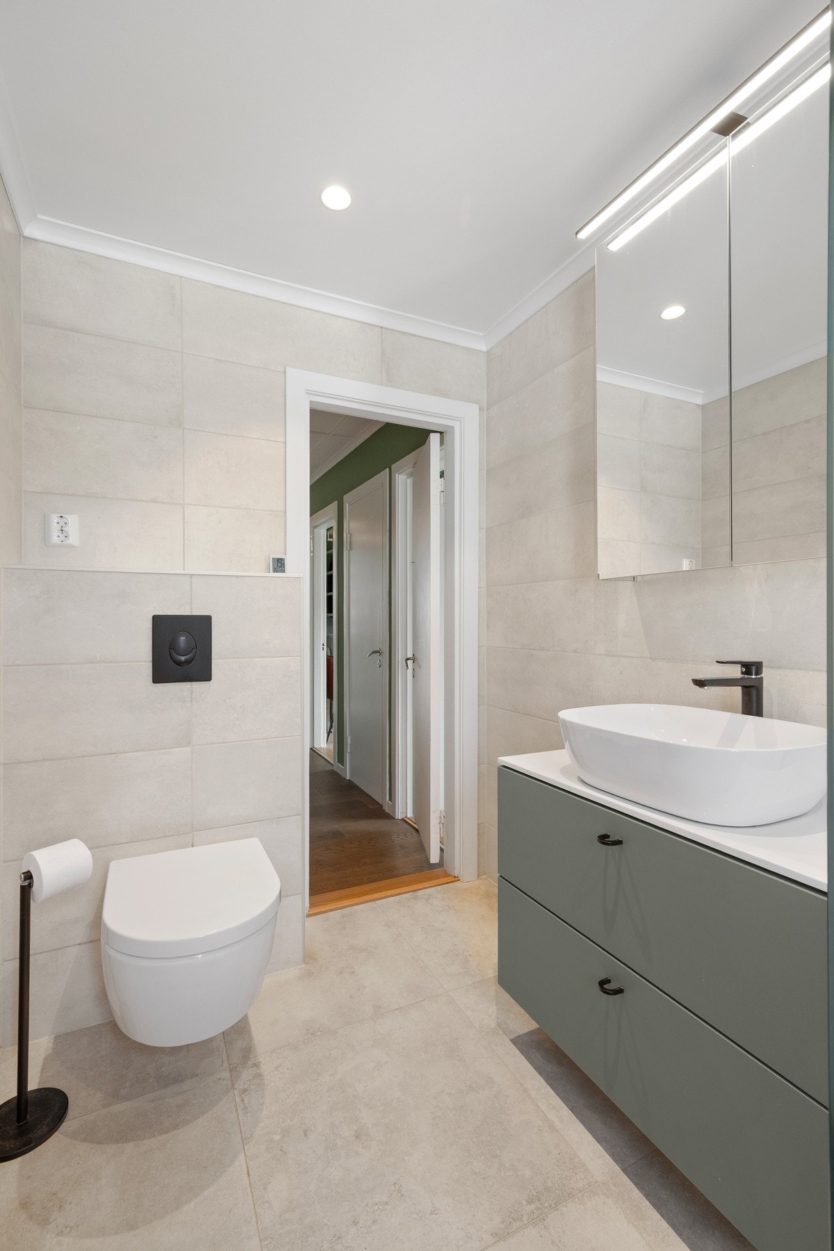 Innredningen består av benkeplate med toppmontert servant og grønne underskuffer, og over servanten er det montert speilskap med belysning. Galleribilde