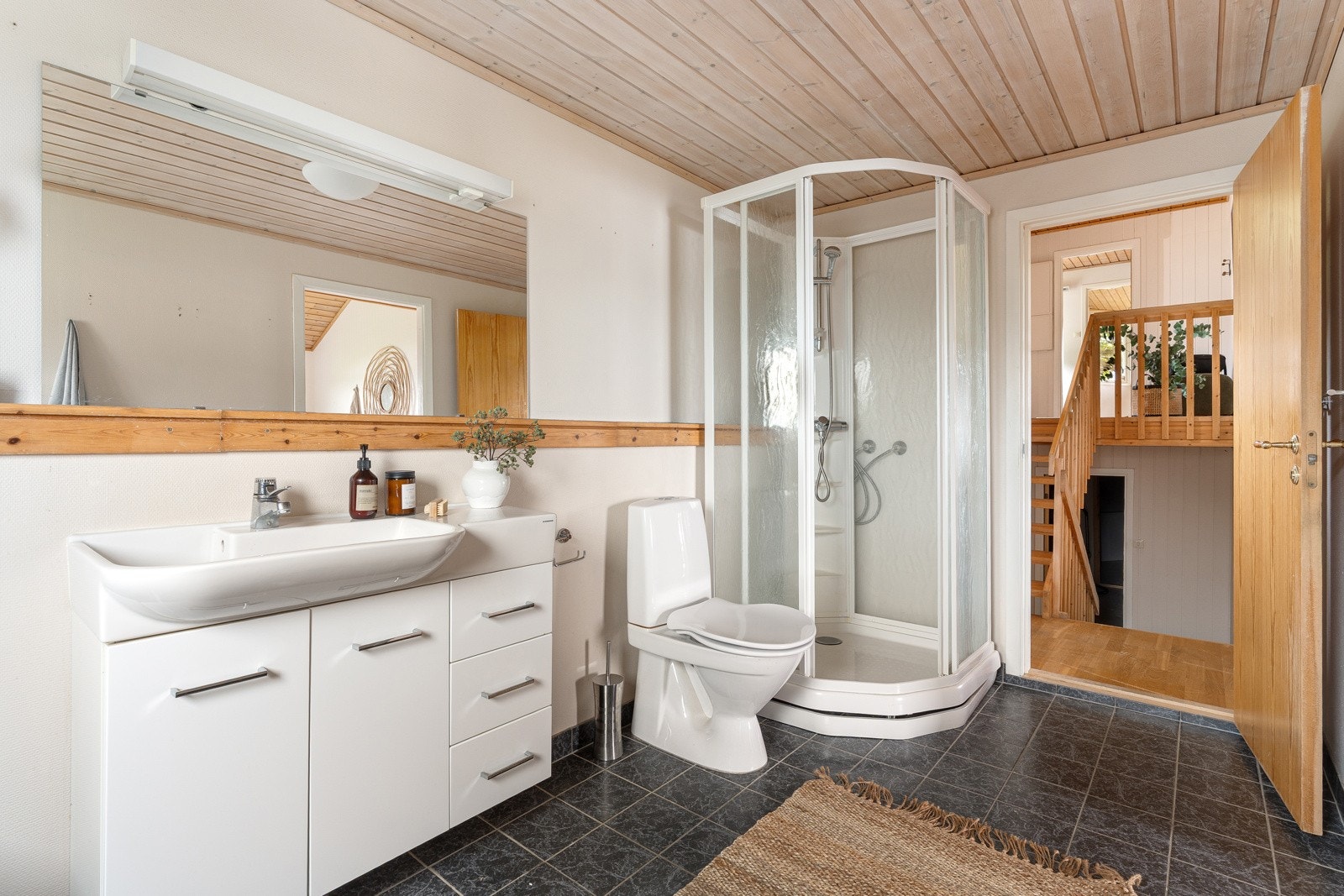 Bad med flislagt gulv, stor servant, badekar og dusjkabinett. Galleribilde