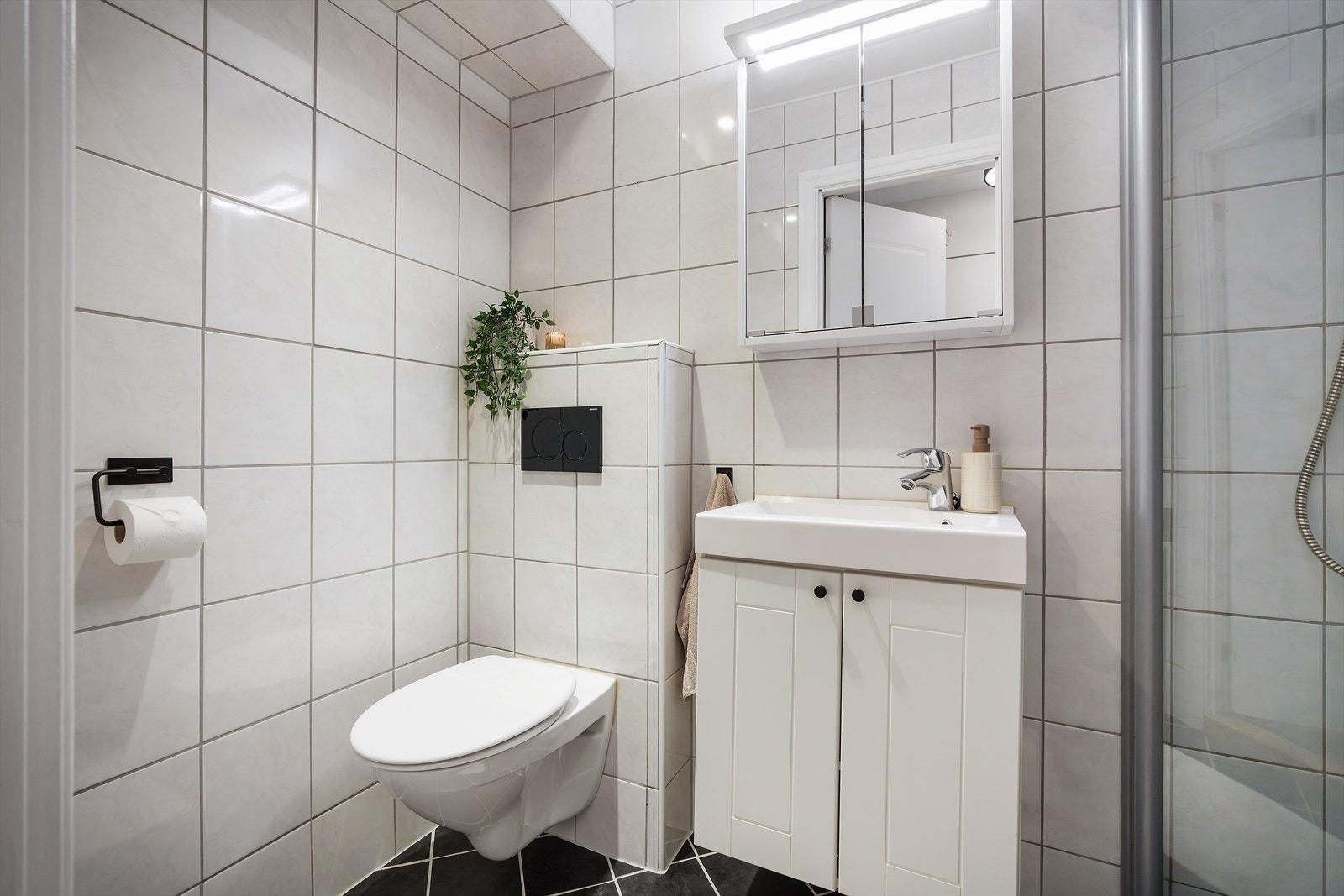 - Badet er innredet med vegghengt toalett, benkeskap med servant og dusjdører i glass - Galleribilde