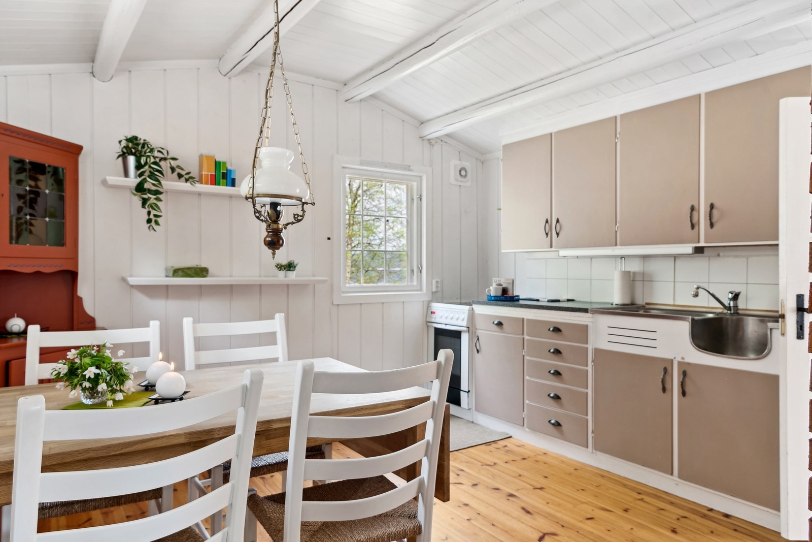 Lyse fliser på veggflatene mellom benkeplaten og overskapene. Det er åpen løsning for komfyr og kjøl-/fryseskap. Avtrekksvifte montert på vegg over komfyr med avkast ført ut av bygget. Galleribilde